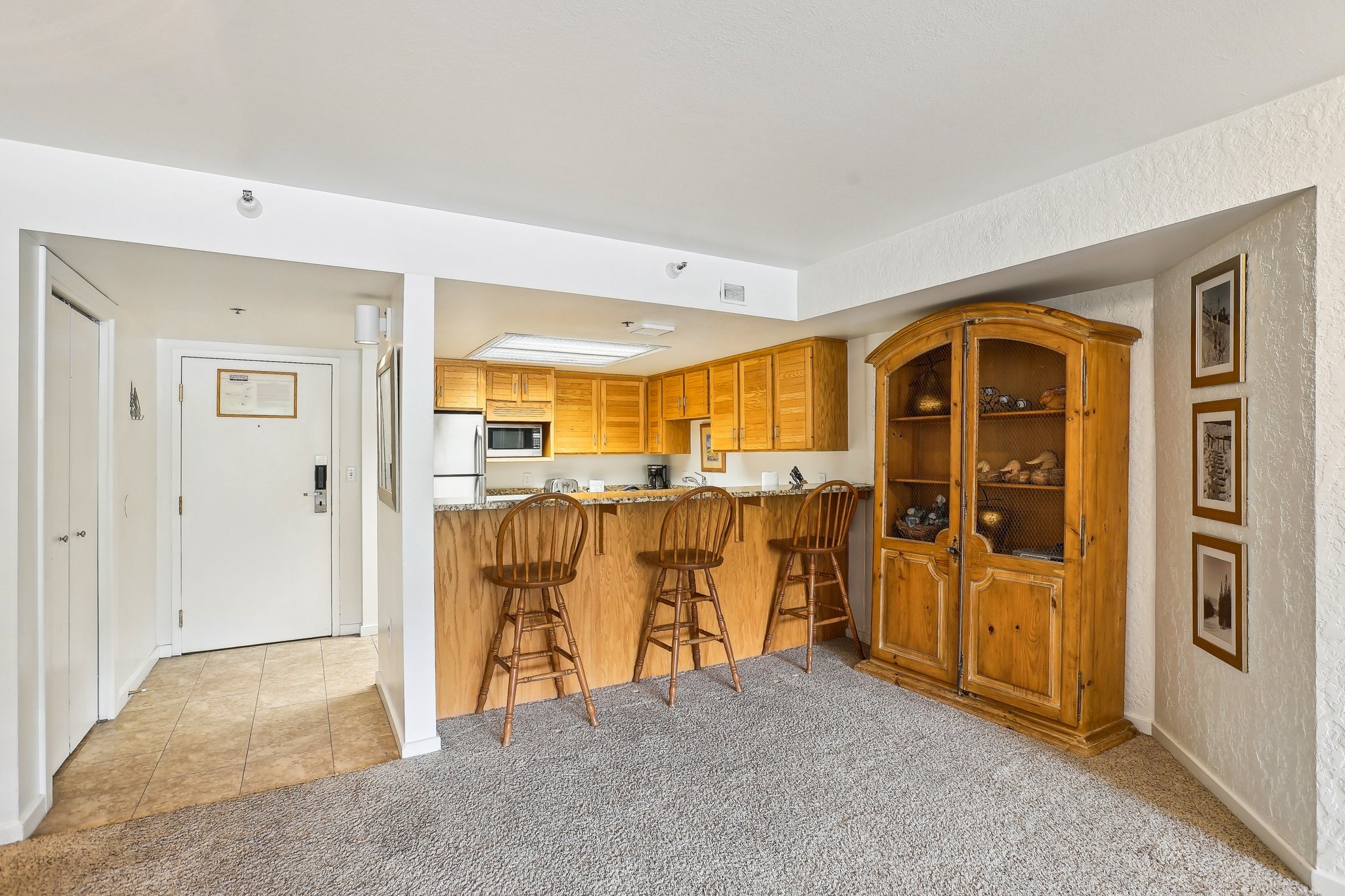 Kitchen area featuring wood cabinetry, stainless steel appliances, and a breakfast bar with a stone-finish countertop