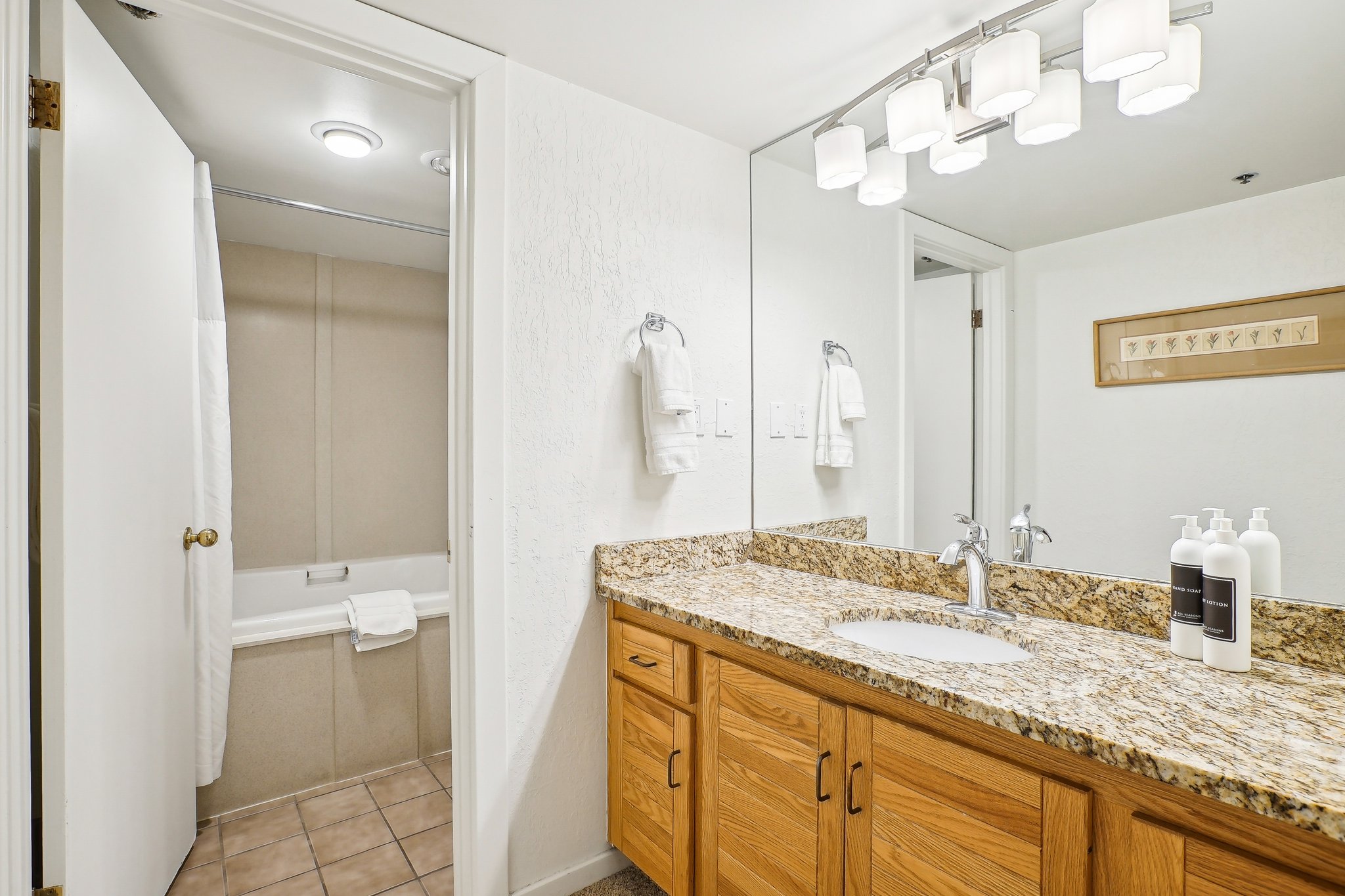 Bathroom vanity featuring a granite-style countertop, undermount sink, and wood-finish cabinetry