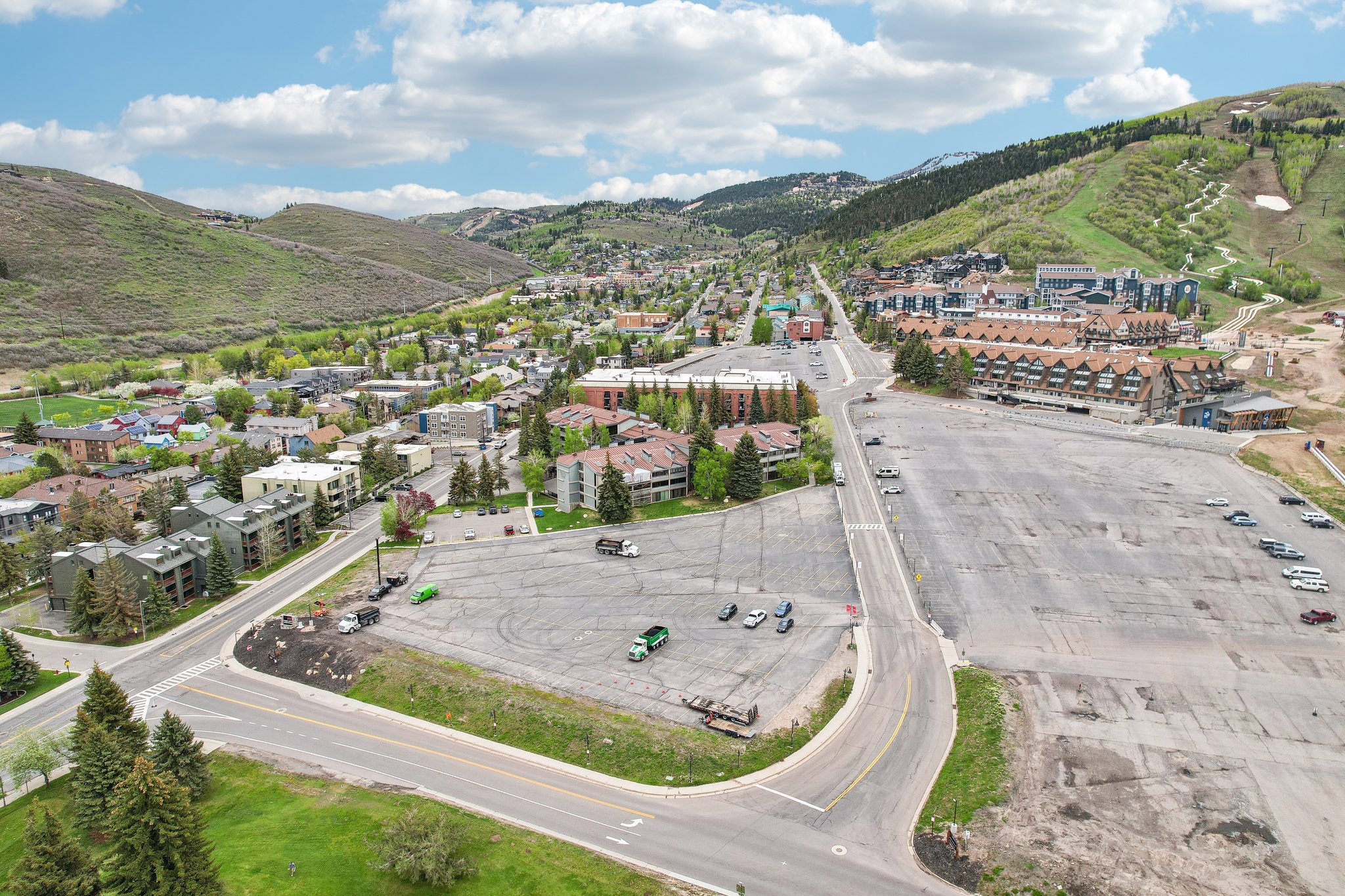 Expansive paved lot with direct road frontage, surrounded by established development and mountainous terrain