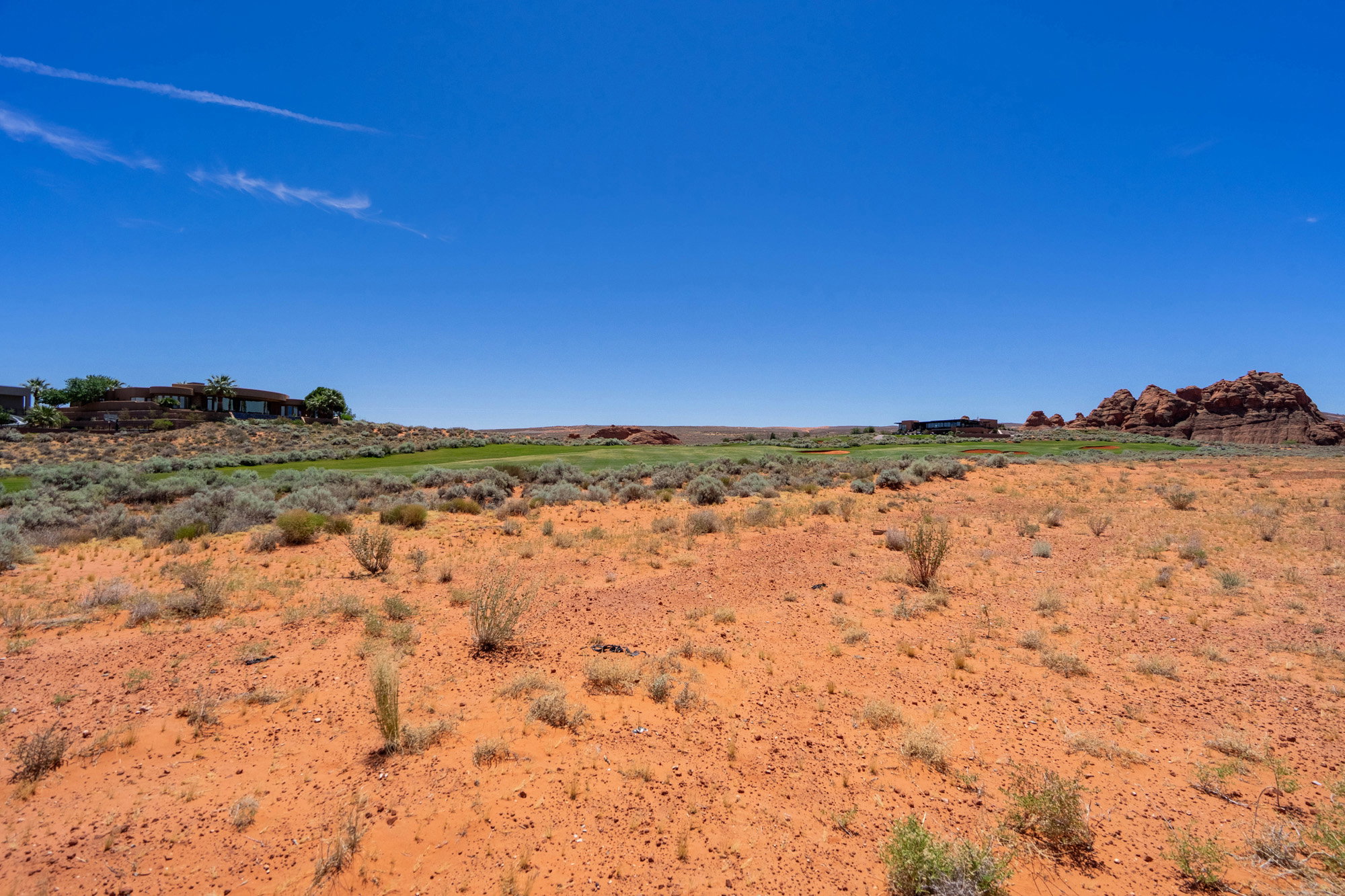 Expansive desert landscape featuring red sand and sparse vegetation