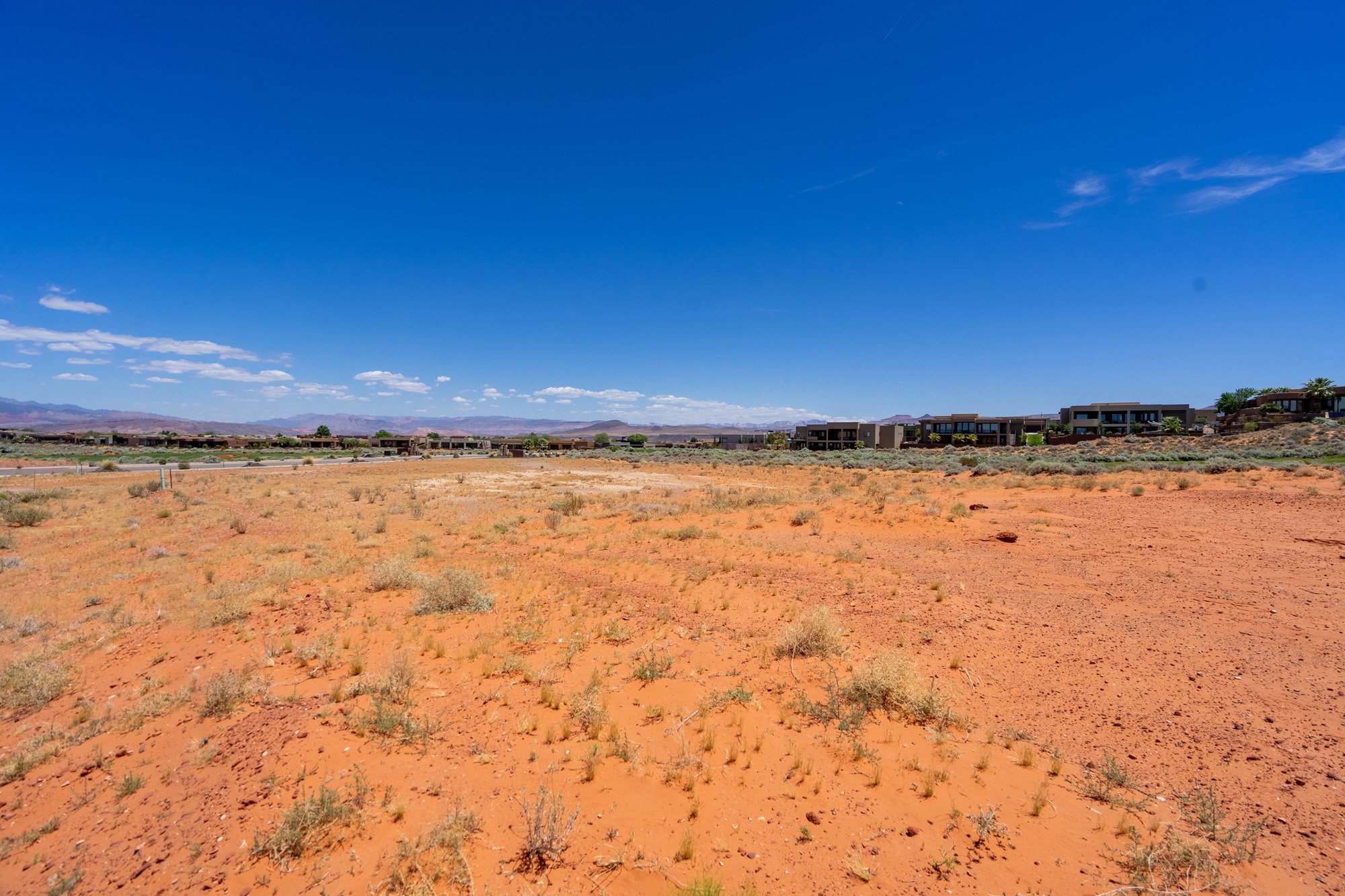 Expansive undeveloped land featuring red earth and sparse desert vegetation
