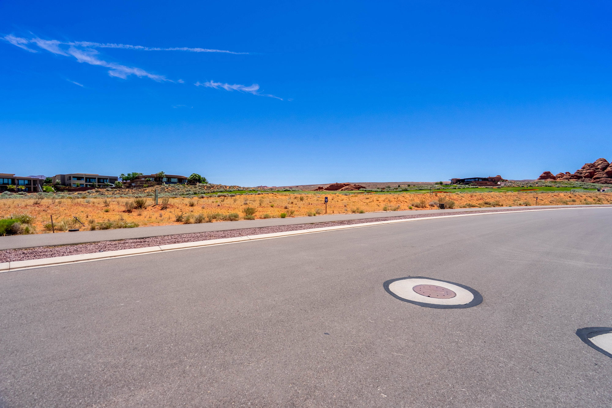 Paved road featuring a concrete sidewalk and arid landscape