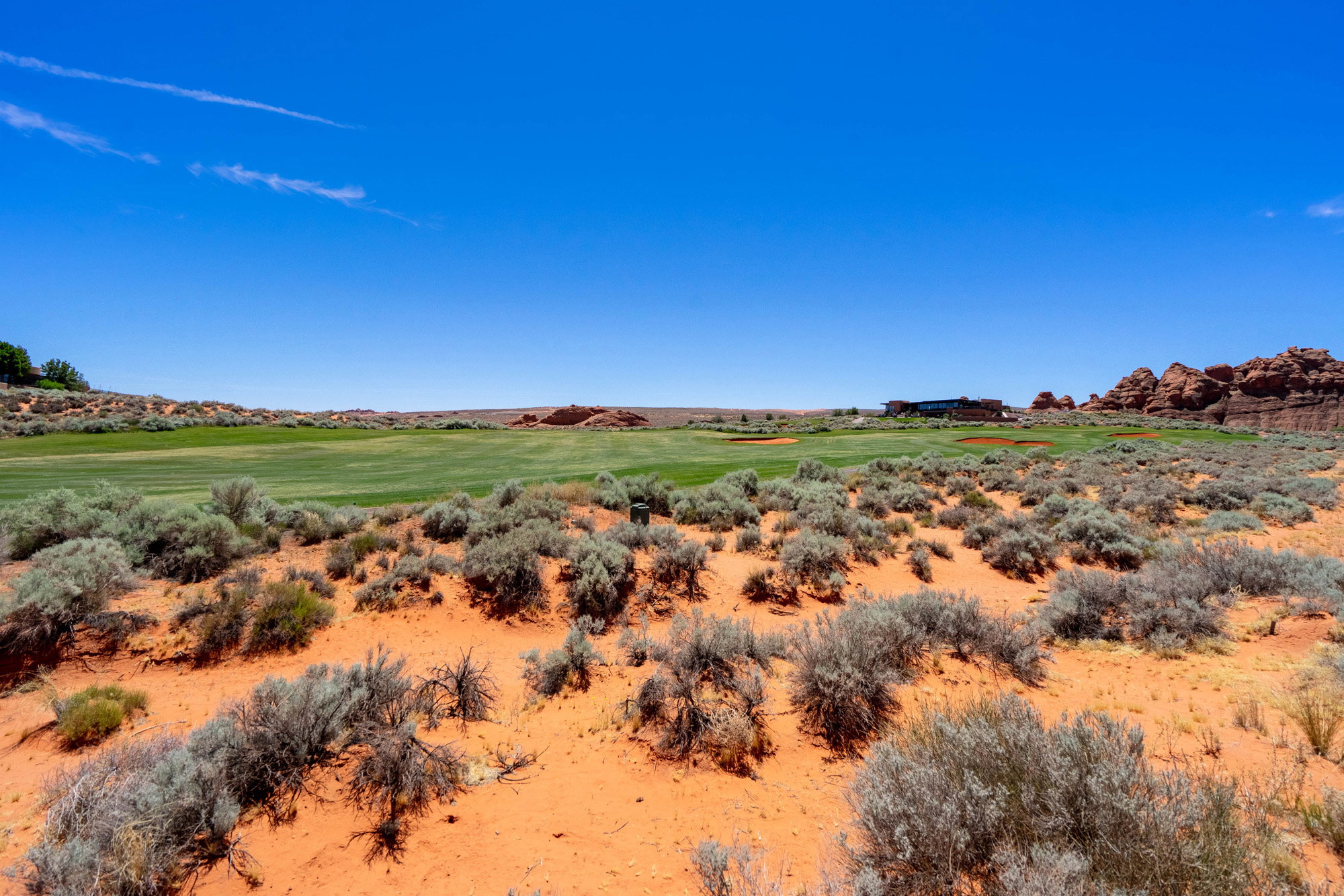 Expansive landscape featuring an arid foreground with green vegetation and a distant golf course