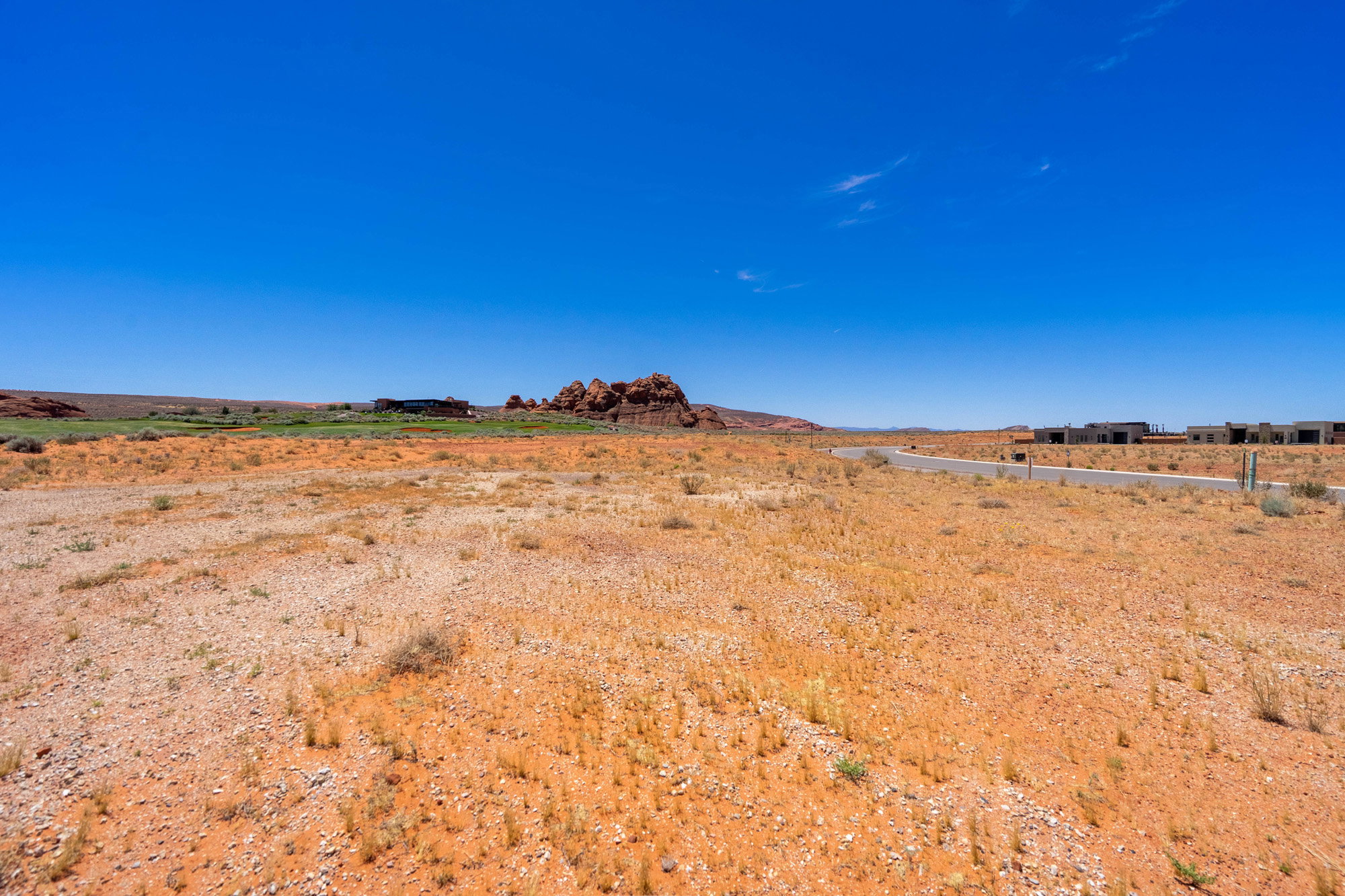 Expansive desert landscape featuring reddish-orange earth and sparse vegetation