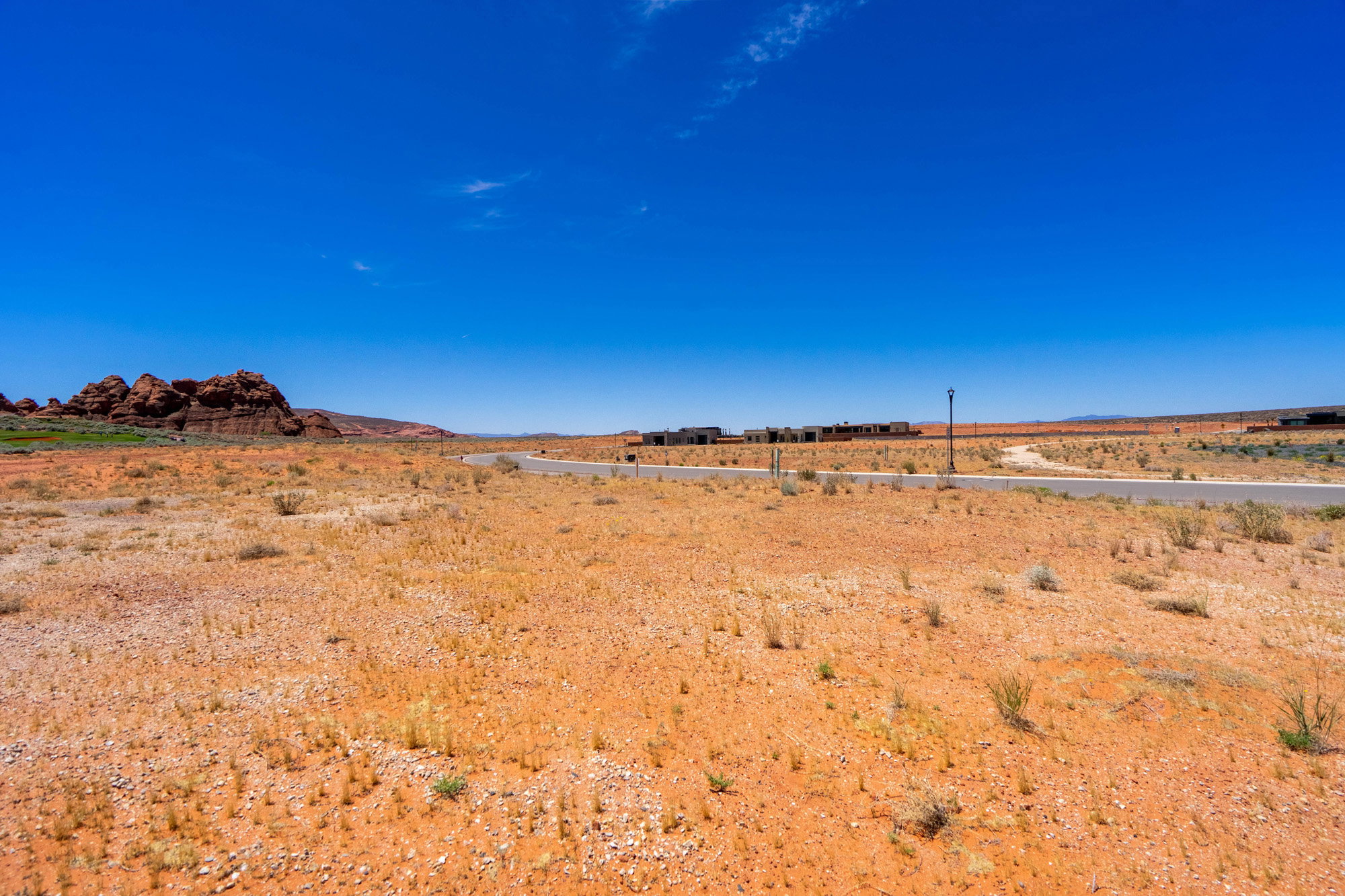Expansive desert landscape featuring natural rock formations and distant structures under a clear sky