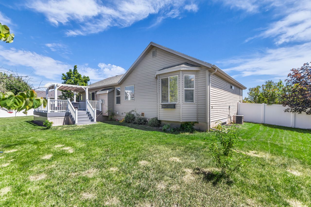 Spacious backyard with a large deck featuring a pergola and stairs