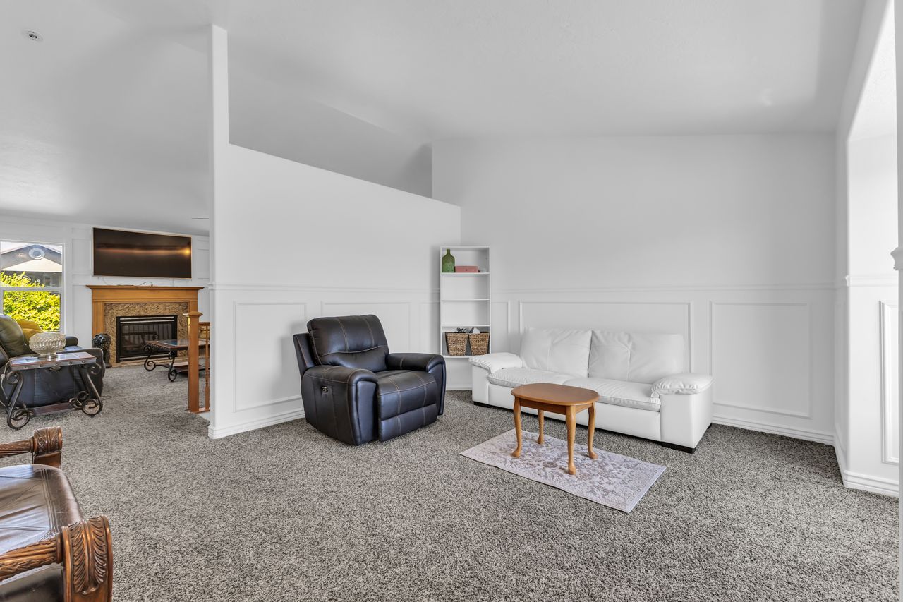 Carpeted living area featuring wainscoting, an open concept layout, and a vaulted ceiling