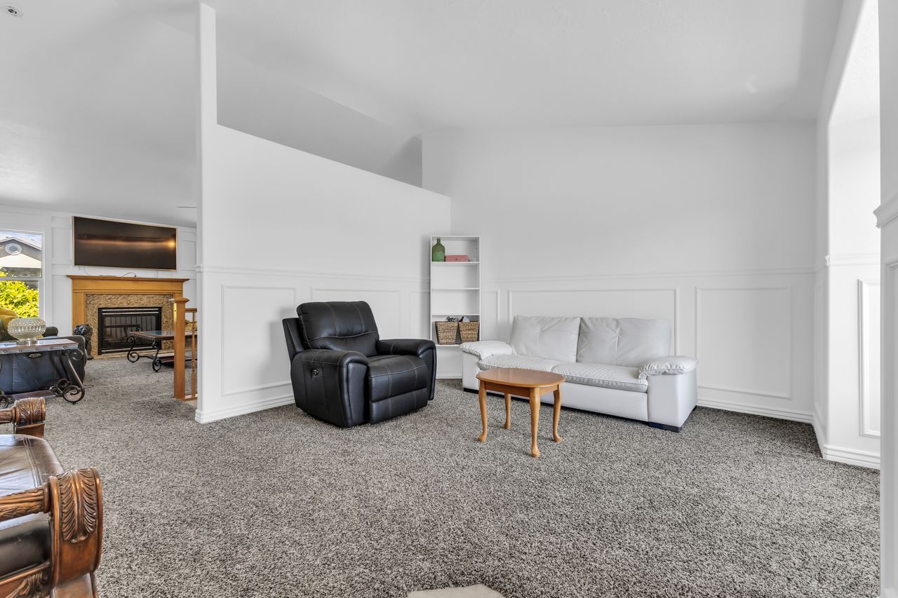 Dedicated living area featuring wainscoting, an integrated shelving unit, and wall-to-wall carpeting