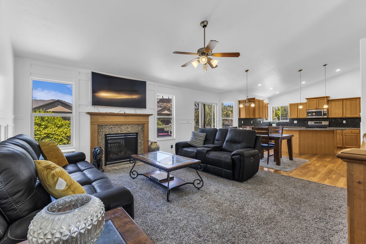 Spacious living area featuring a fireplace with a stone surround and wood mantel, complemented by a ceiling fan