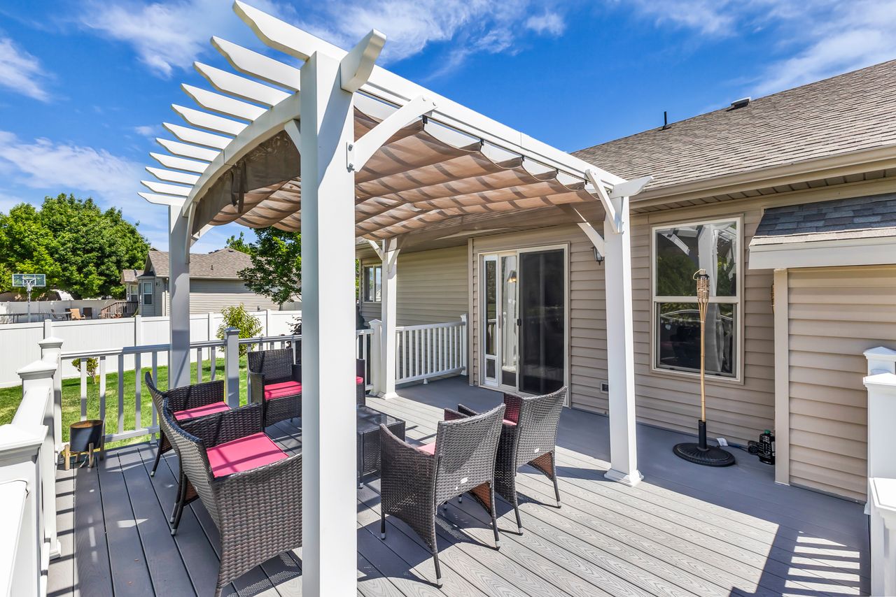 Composite deck featuring a retractable pergola, white railing, and sliding glass door access to the interior