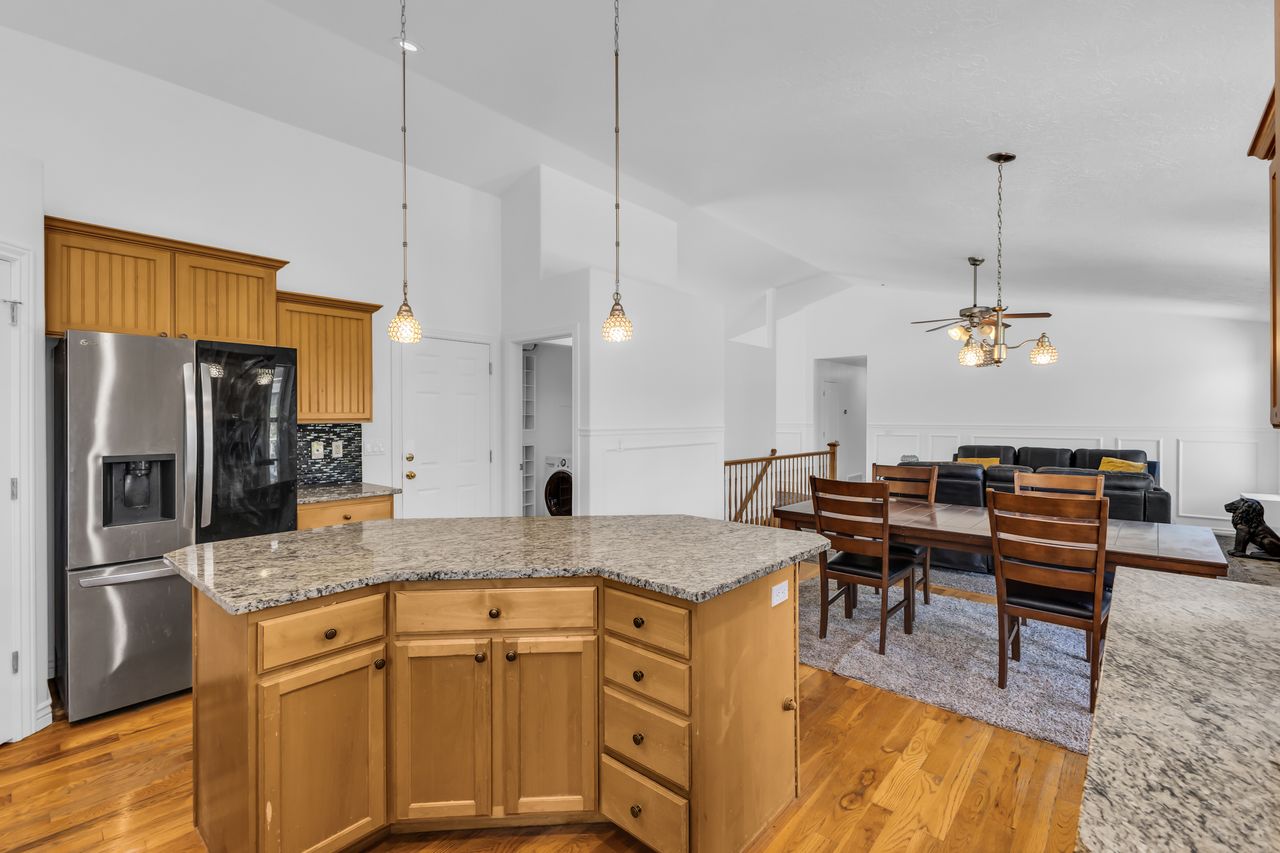 Kitchen island featuring a light-toned wood base with granite-finish countertops