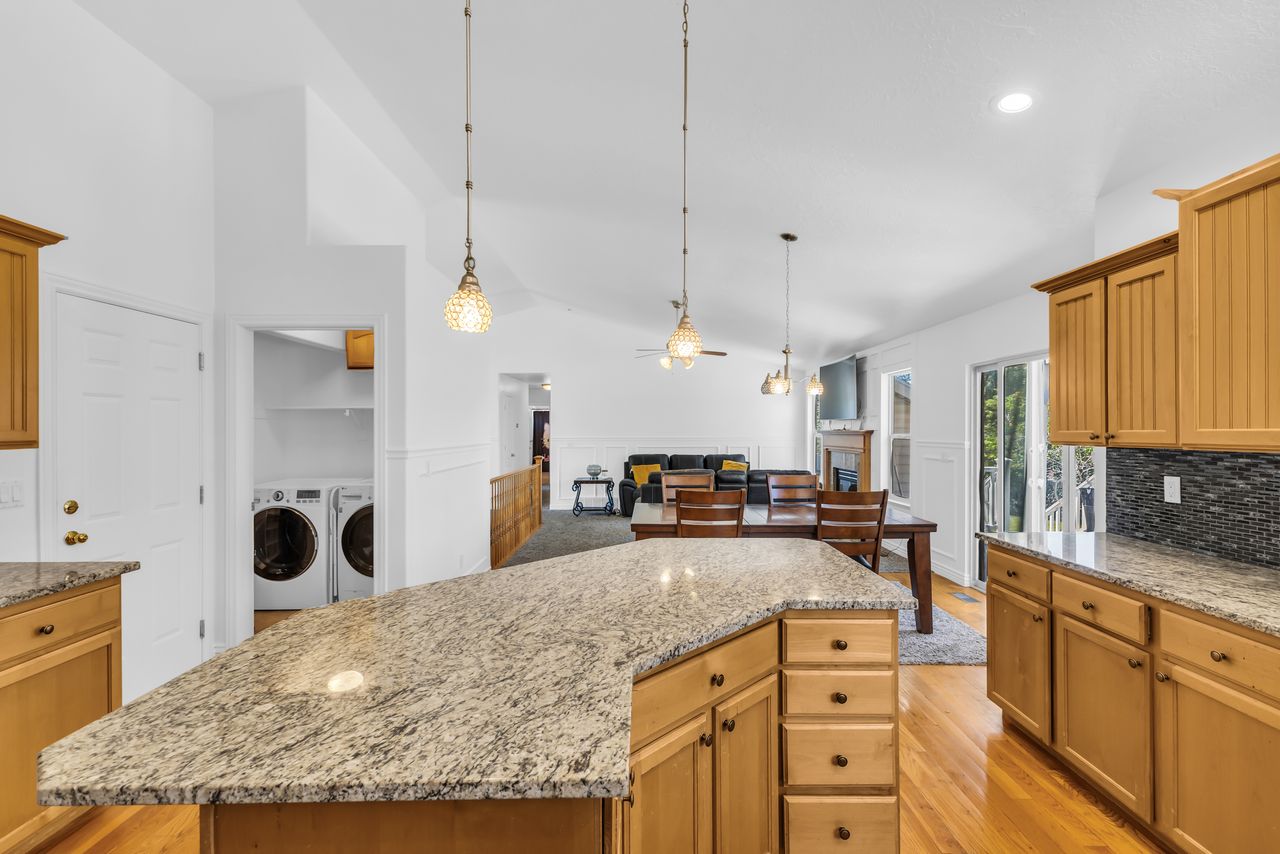 Kitchen featuring an expansive island with a light-toned countertop, wood-finish cabinetry, and pendant lighting