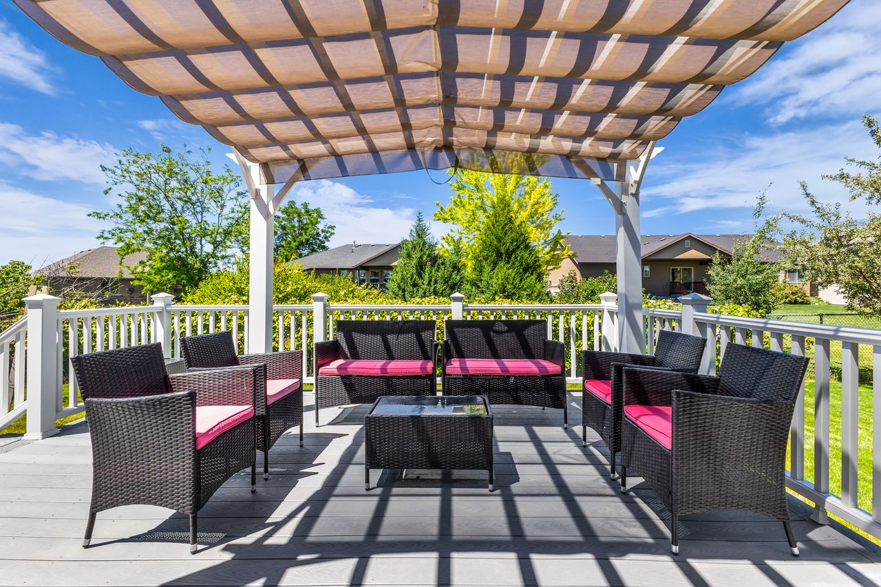 Expansive outdoor deck featuring a shade pergola with a retractable canopy, durable composite decking, and white railing