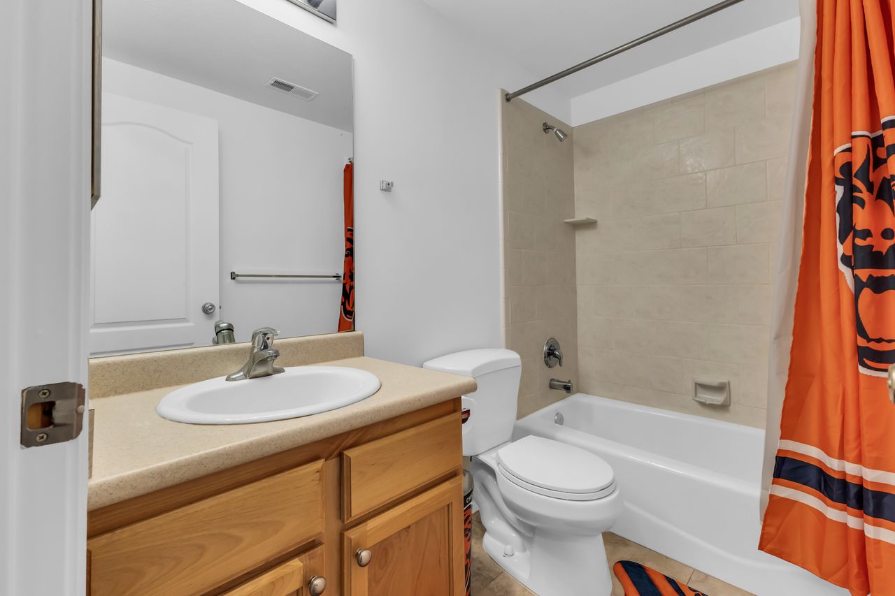 Bathroom featuring a single vanity with an integrated sink, wood-finish cabinetry, and a beige countertop