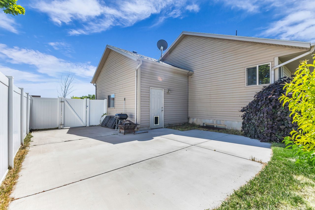 Concrete patio area with a white vinyl privacy fence and gate