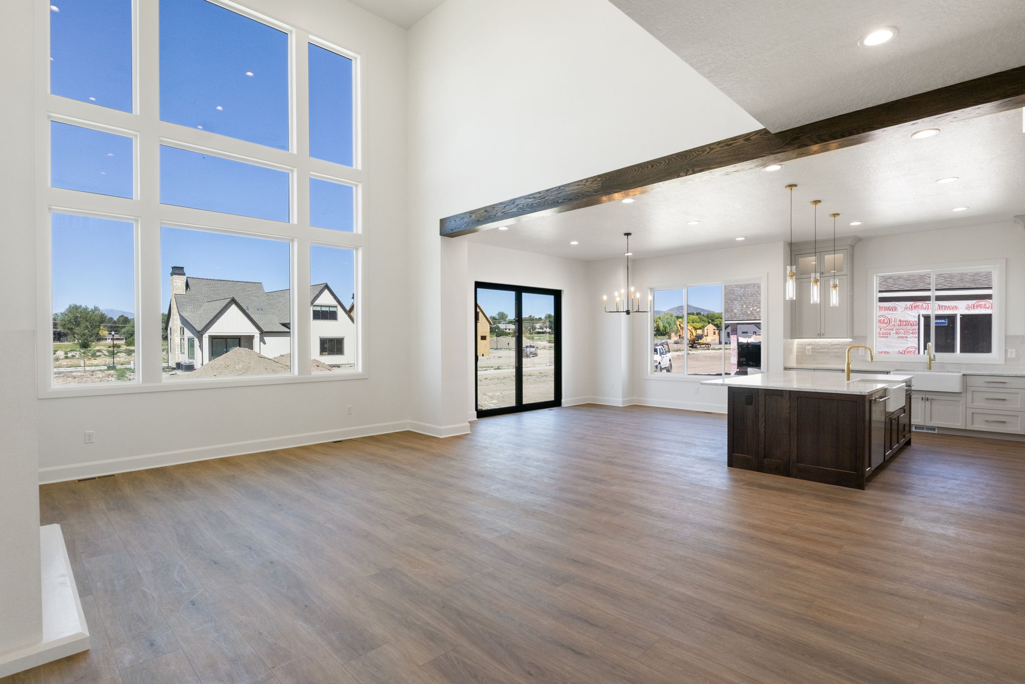 Spacious living area featuring expansive multi-pane windows, wood-finish flooring, and high ceilings