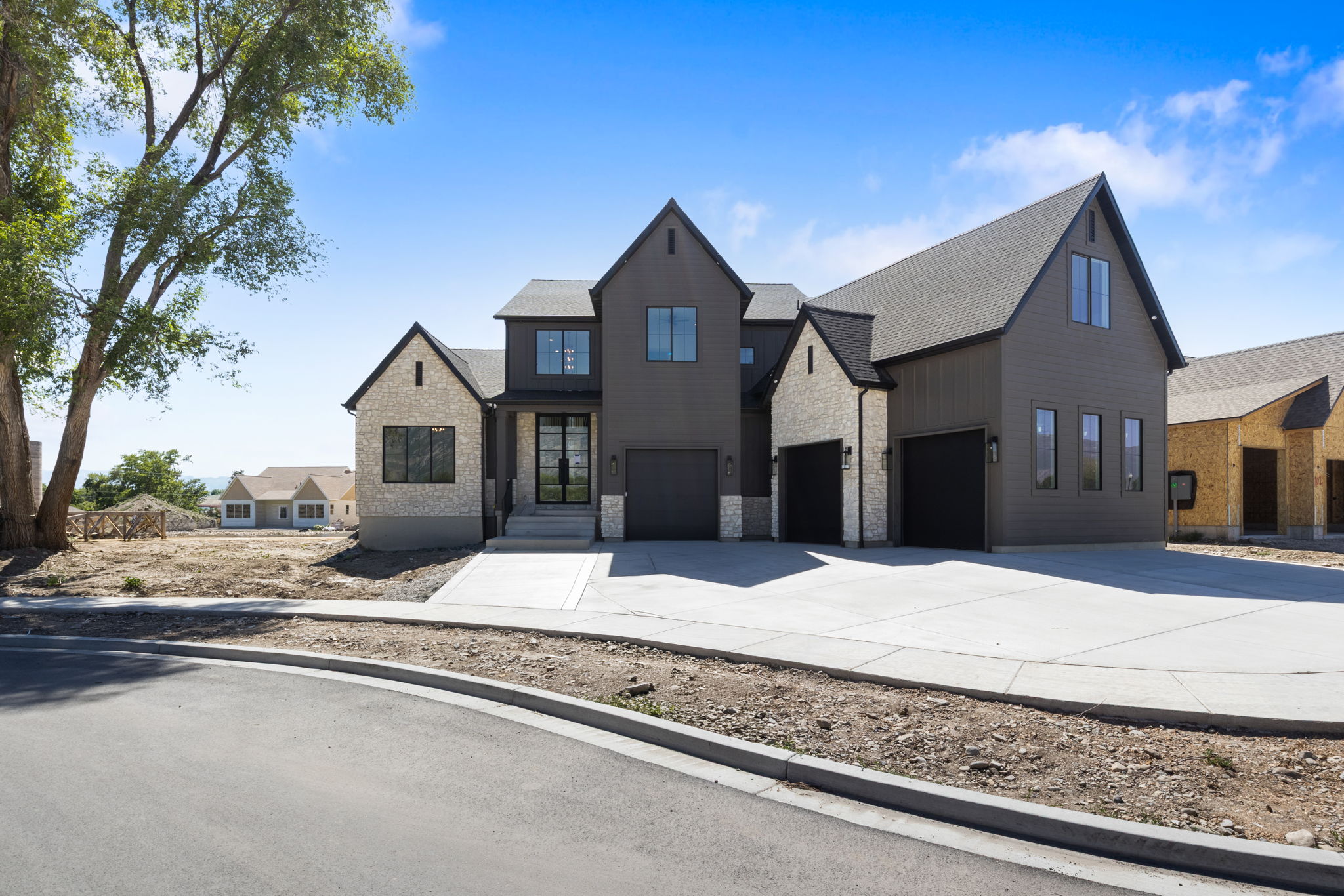 Modern farmhouse exterior featuring dark vertical siding and light-colored stone accents