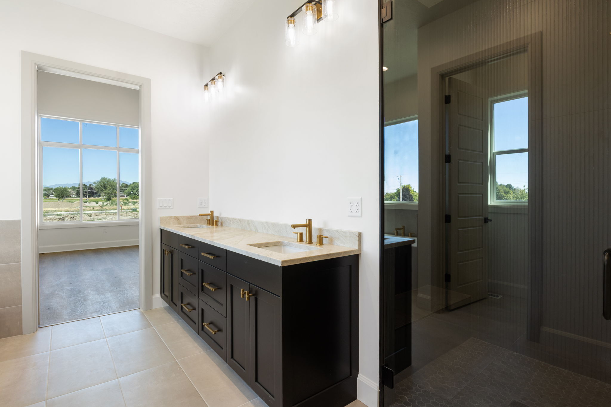 Double vanity with stone countertop and gold-finish fixtures