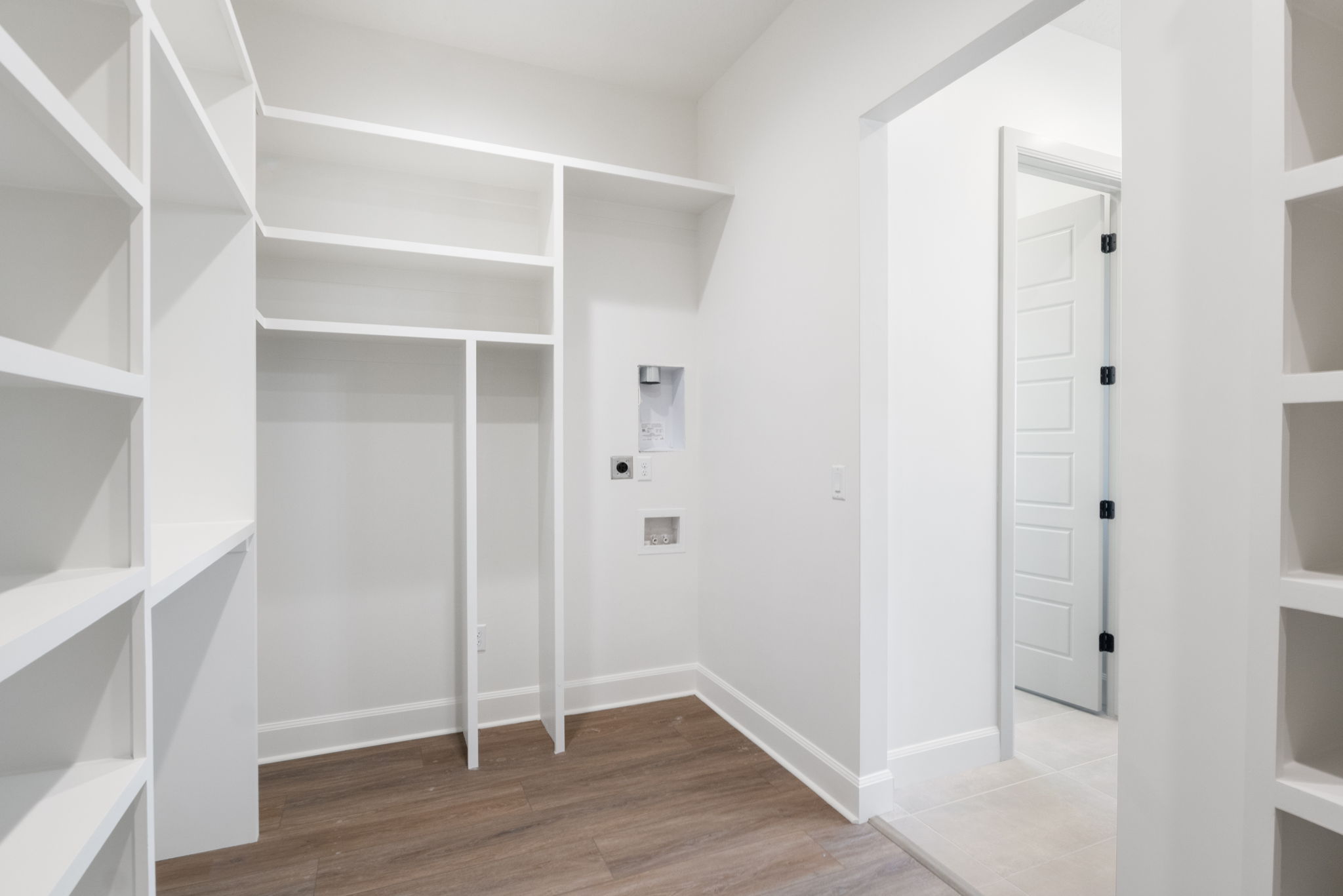 Laundry area featuring wood-finish flooring and extensive built-in shelving