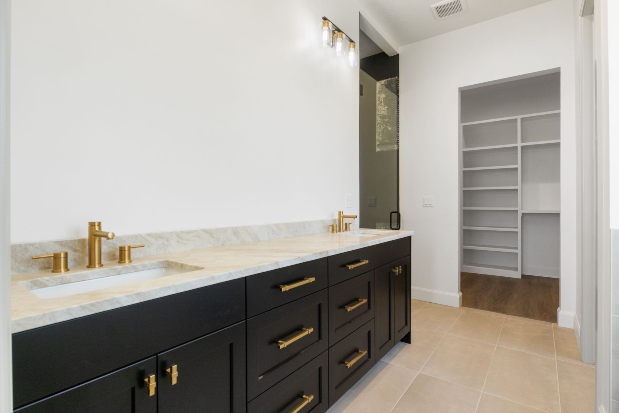 Double vanity featuring a light-toned countertop with integrated sinks and brass-finish hardware