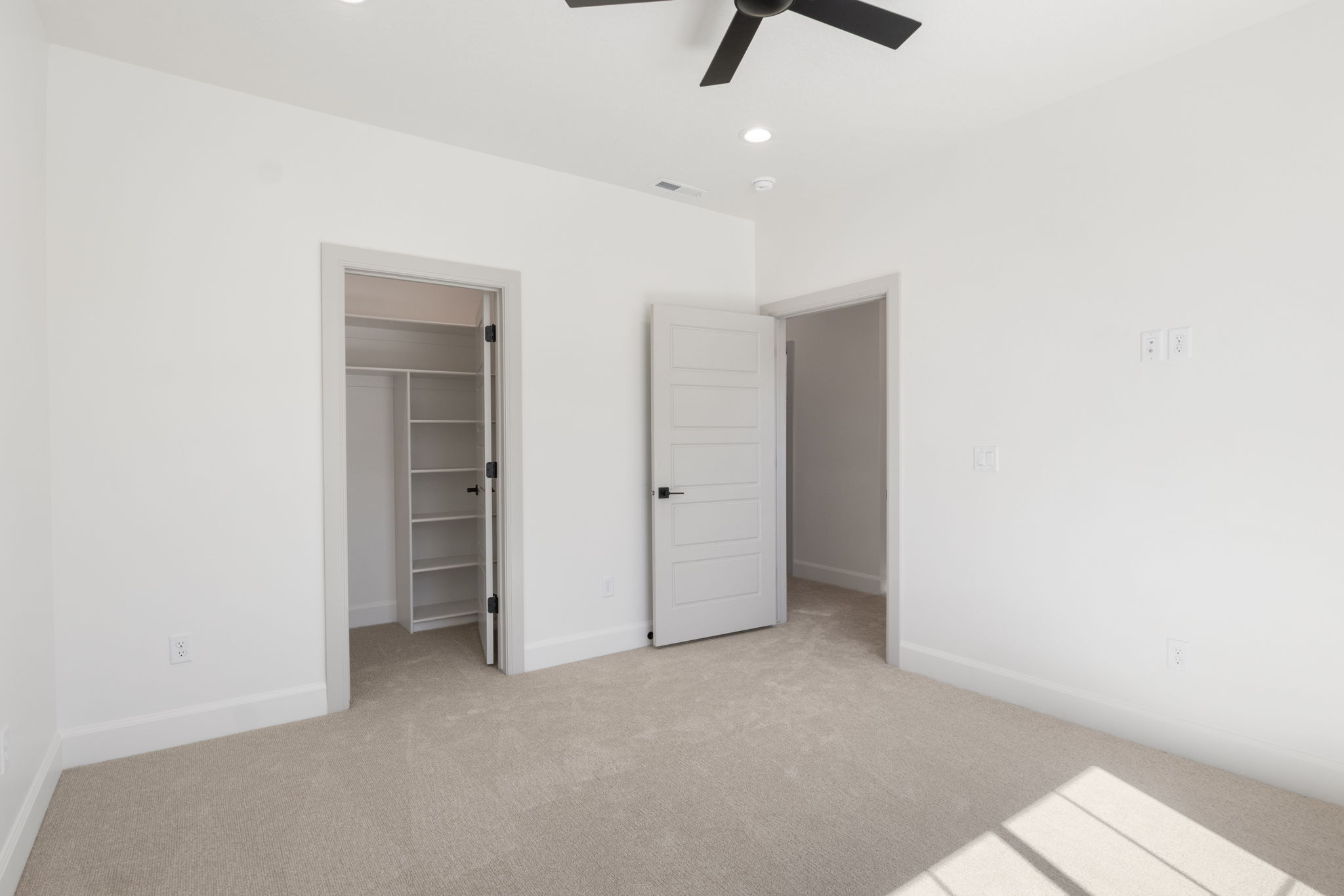 Neutral tone carpeted room featuring white walls and baseboards