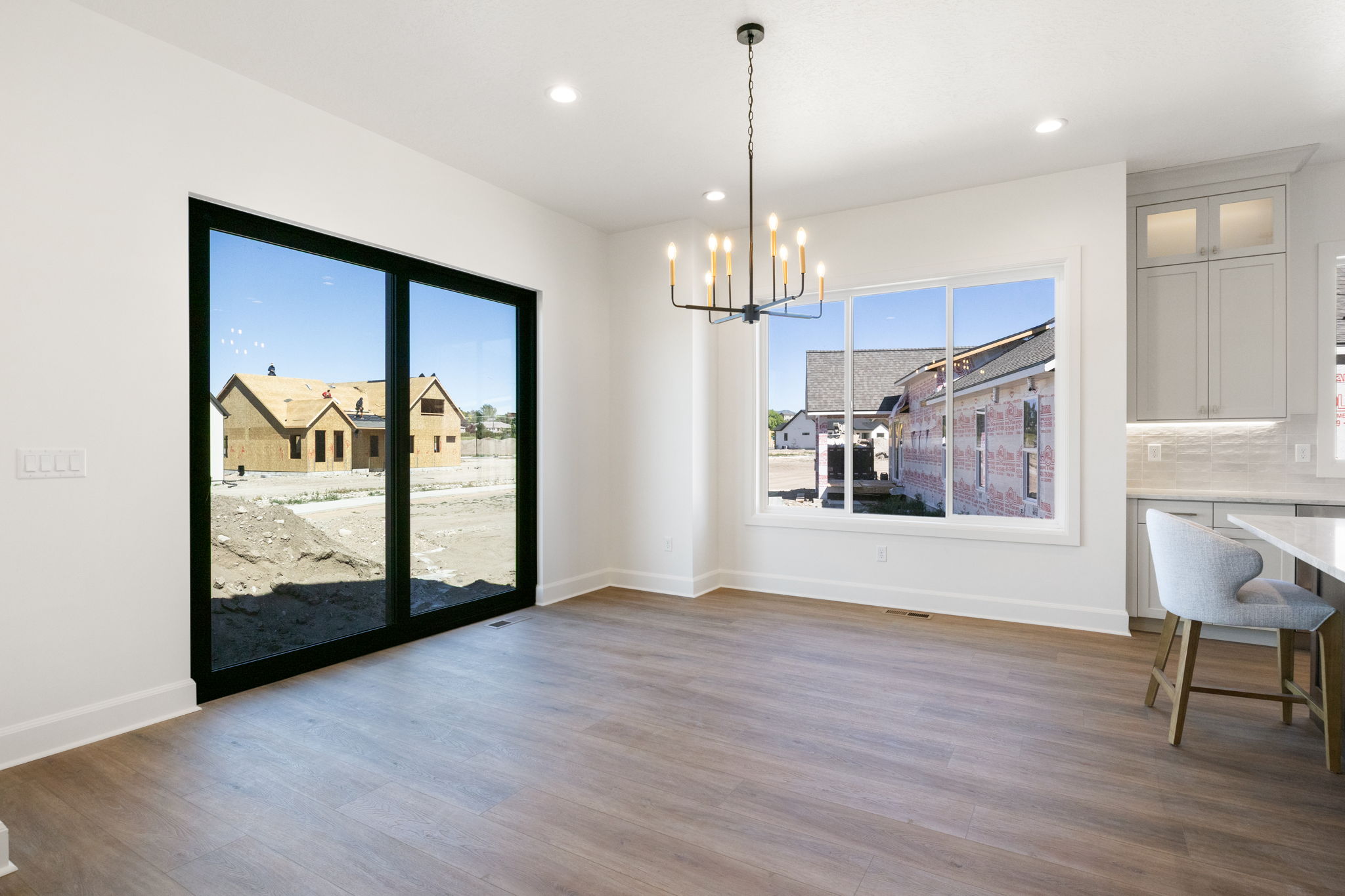 Open-concept living area with wood-finish flooring, a contemporary chandelier, recessed lighting, and white baseboards
