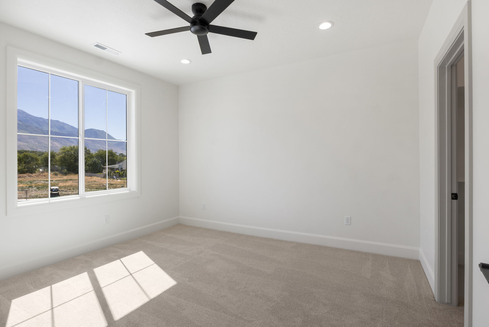 Bright room featuring a large window with mountain scenery, plush carpet, recessed lighting, a ceiling fan, and painted baseboards