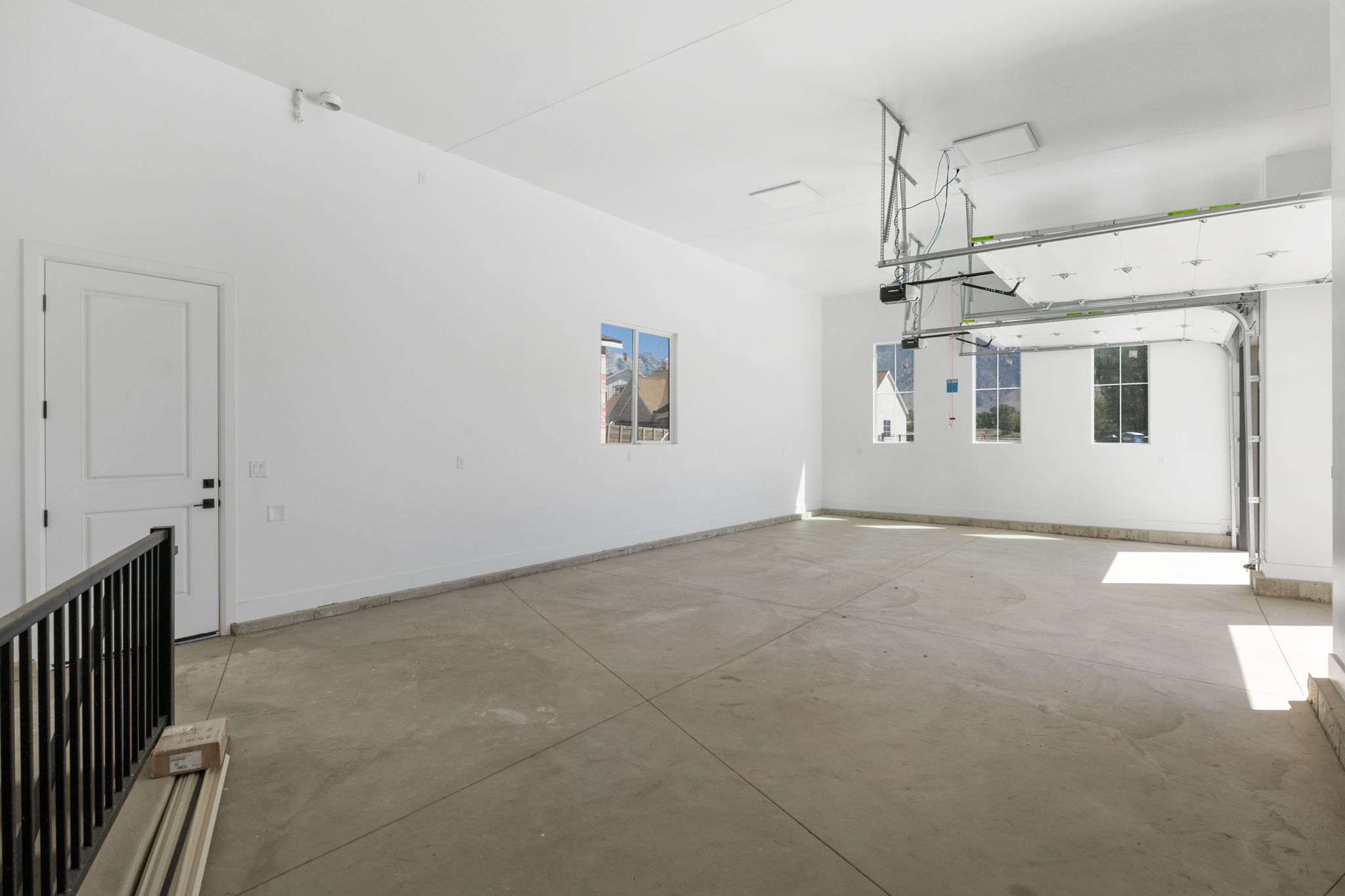 Spacious garage featuring a concrete floor, bright white walls, multiple windows, and a large overhead door