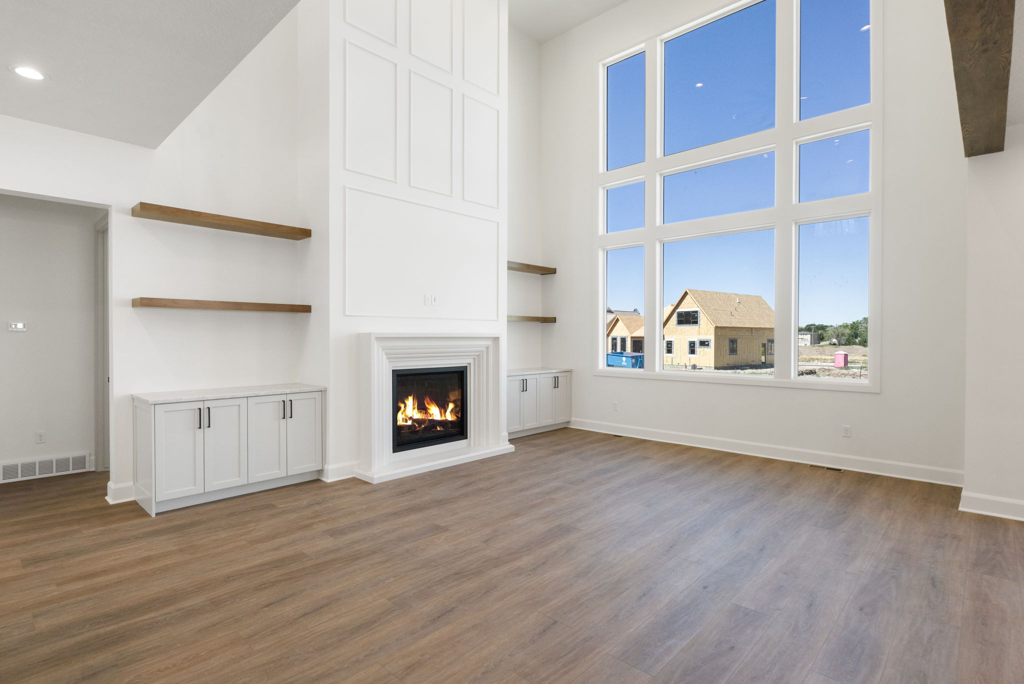 Spacious living area featuring a tall fireplace with decorative paneling and an expansive window wall