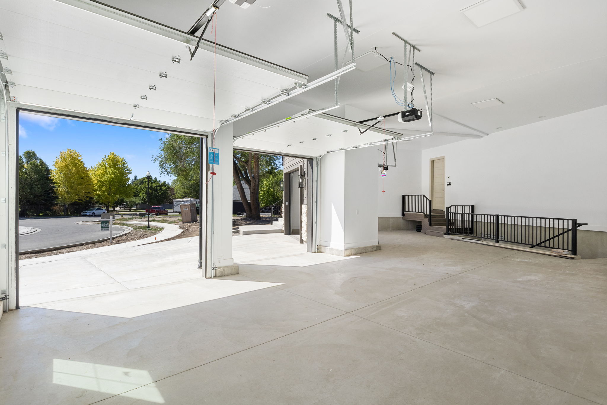 Spacious garage featuring a concrete floor, white walls, and an open garage door leading to an exterior driveway