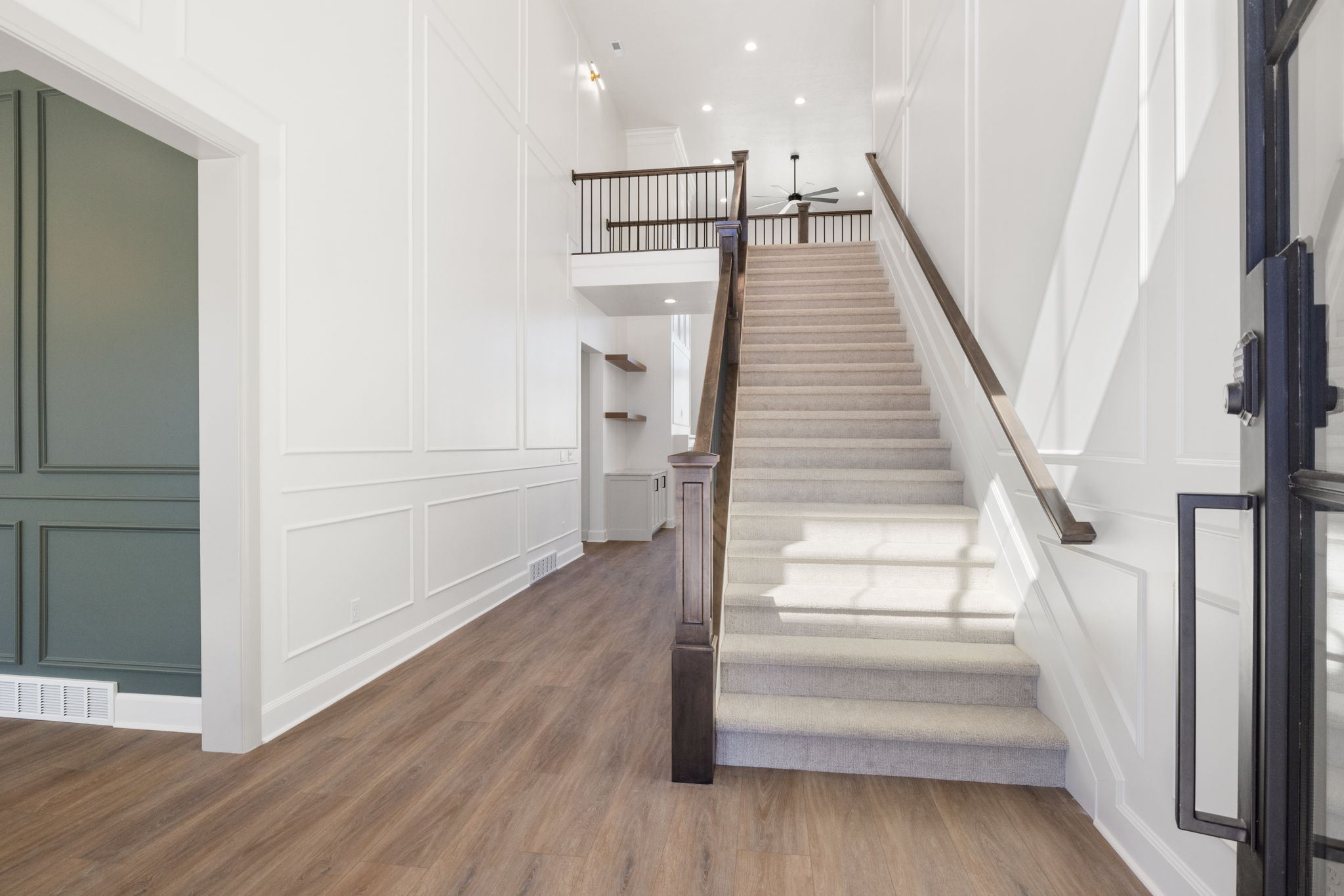 Two-story foyer featuring wood-finish flooring and wainscoting