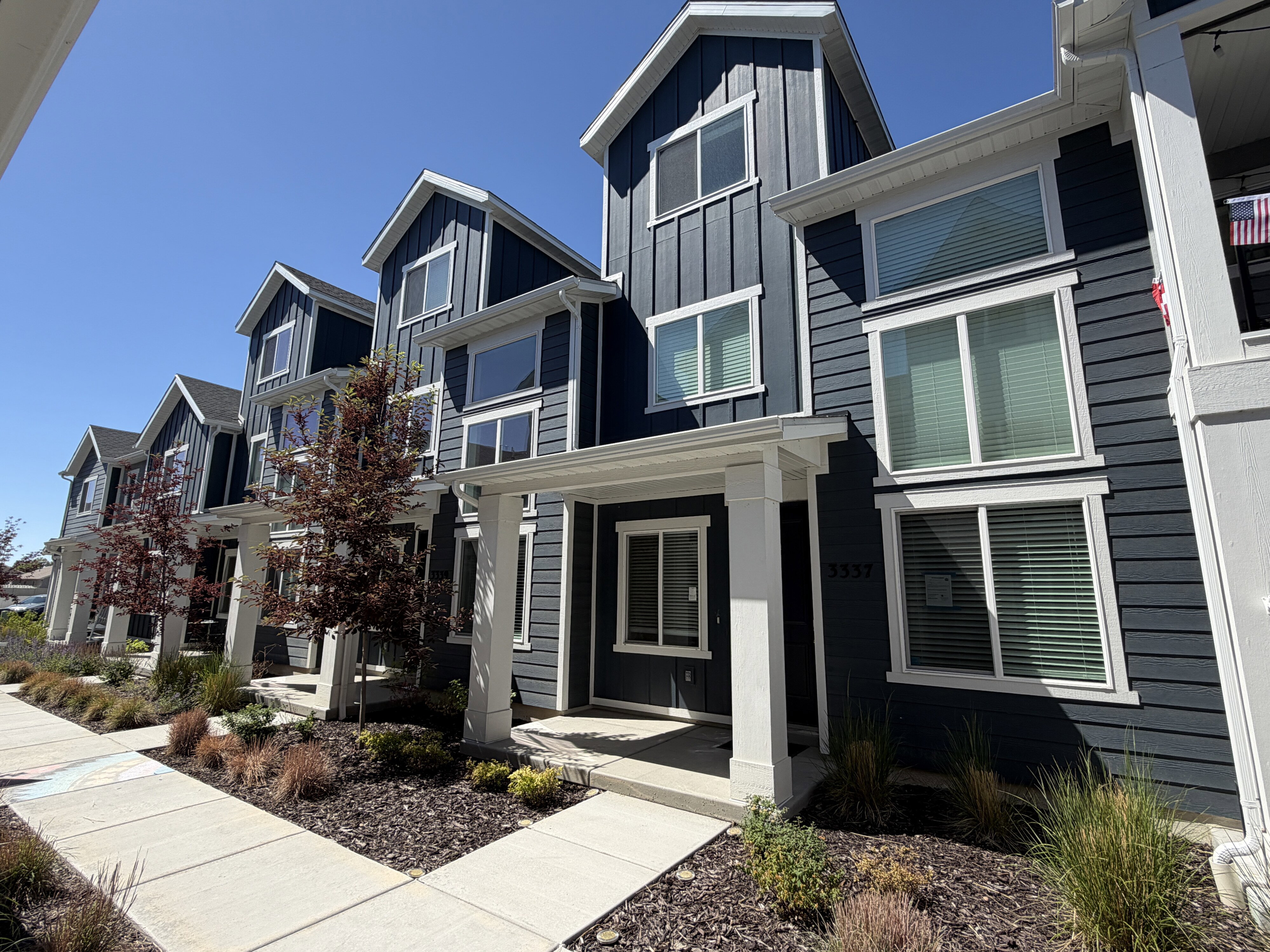 Modern townhome exterior featuring multi-level architecture with a dark gray vertical and horizontal siding facade