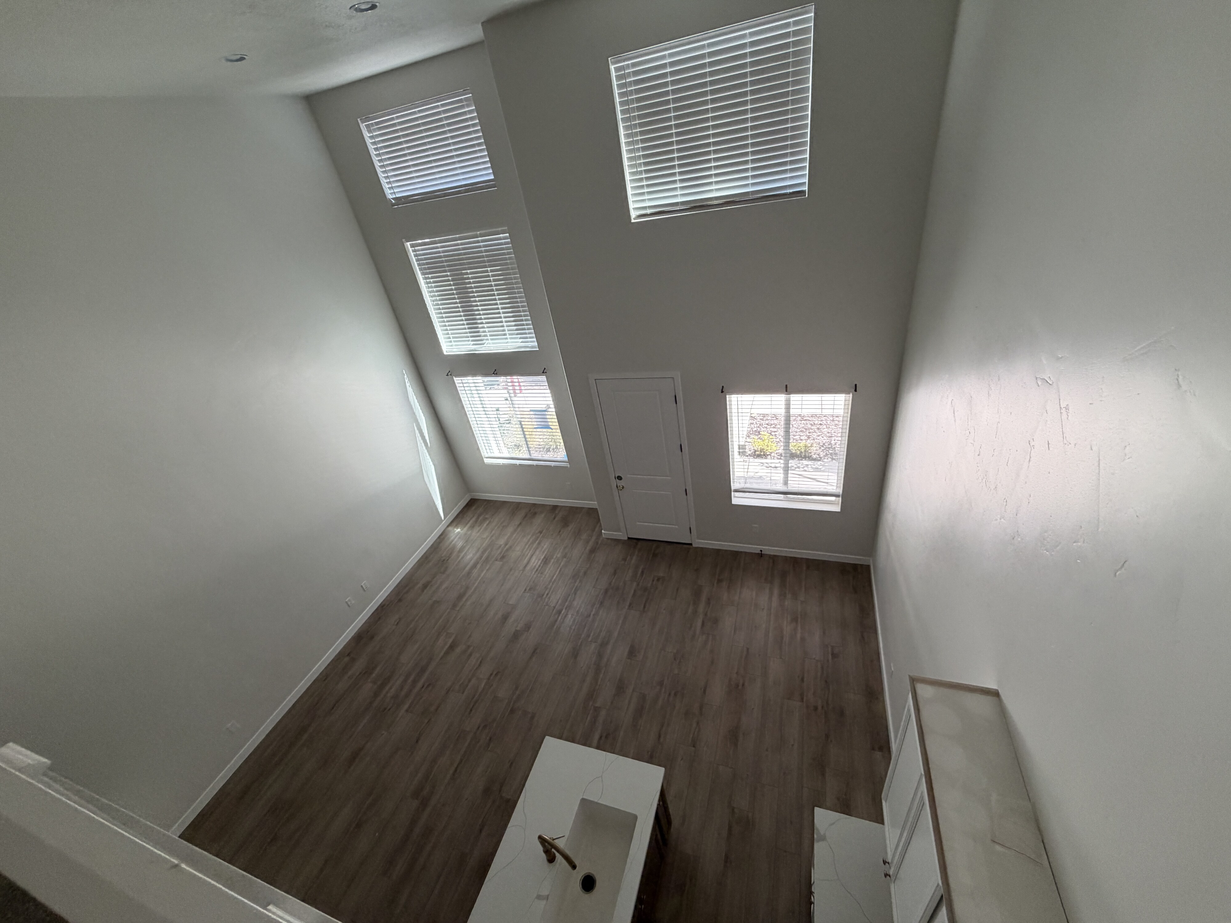 Two-story living area featuring wood-finish flooring and a vaulted ceiling with multiple windows