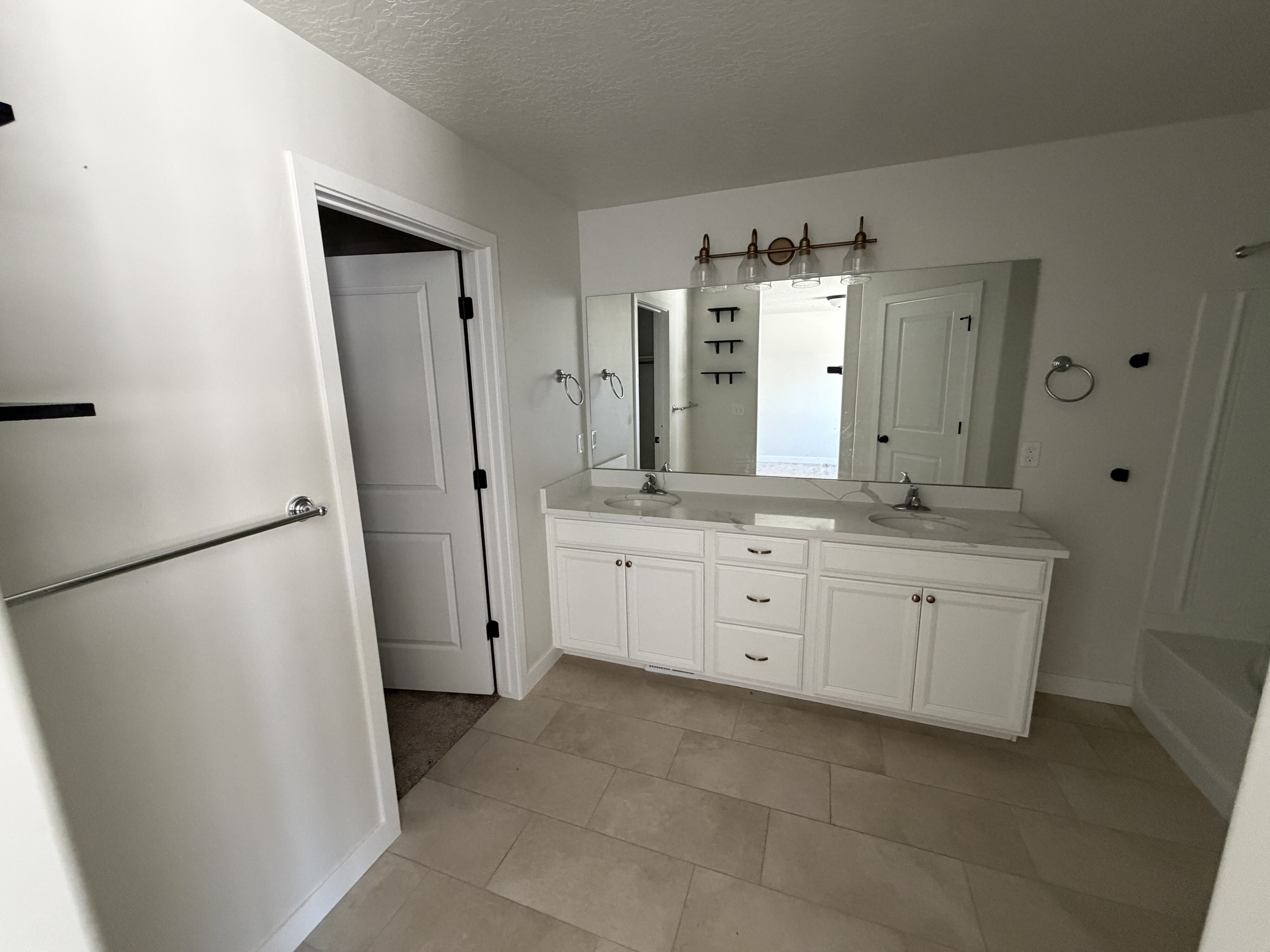 Bathroom featuring a double vanity with white cabinetry, light-toned countertop, and two undermount sinks
