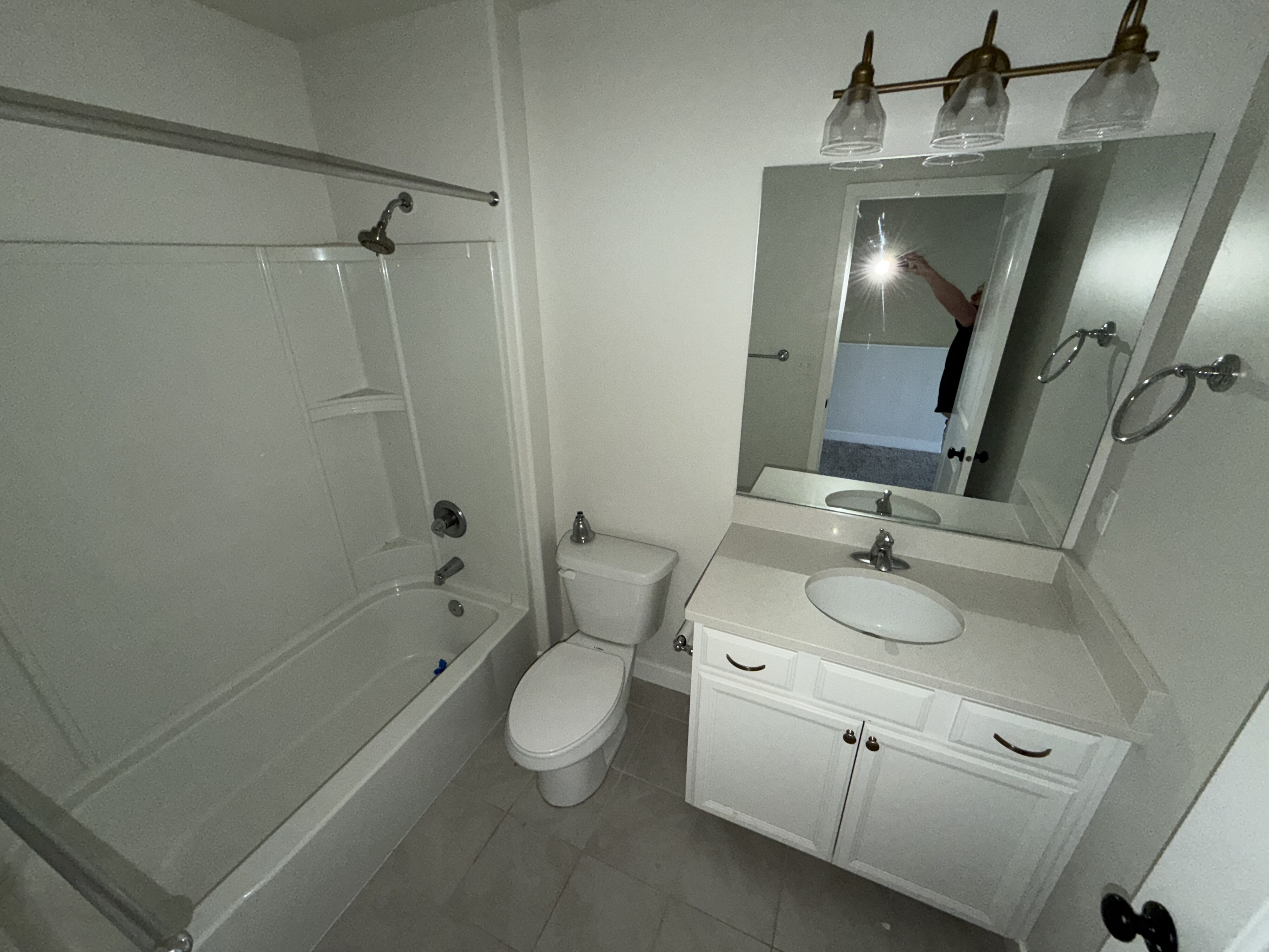 Bathroom featuring a white vanity with an oval sink, light-colored countertop, and two-door cabinetry with dark hardware