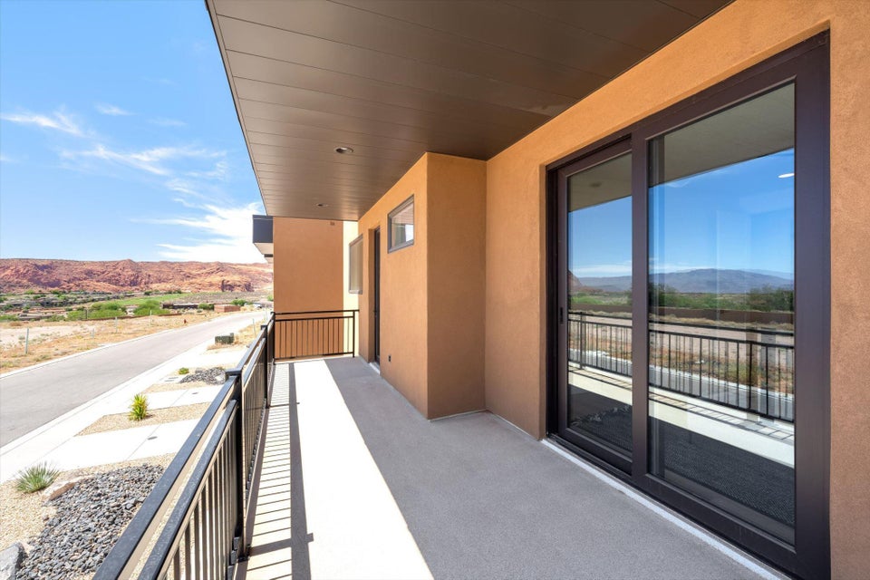 Expansive balcony featuring concrete flooring, black metal railings, and a stucco exterior