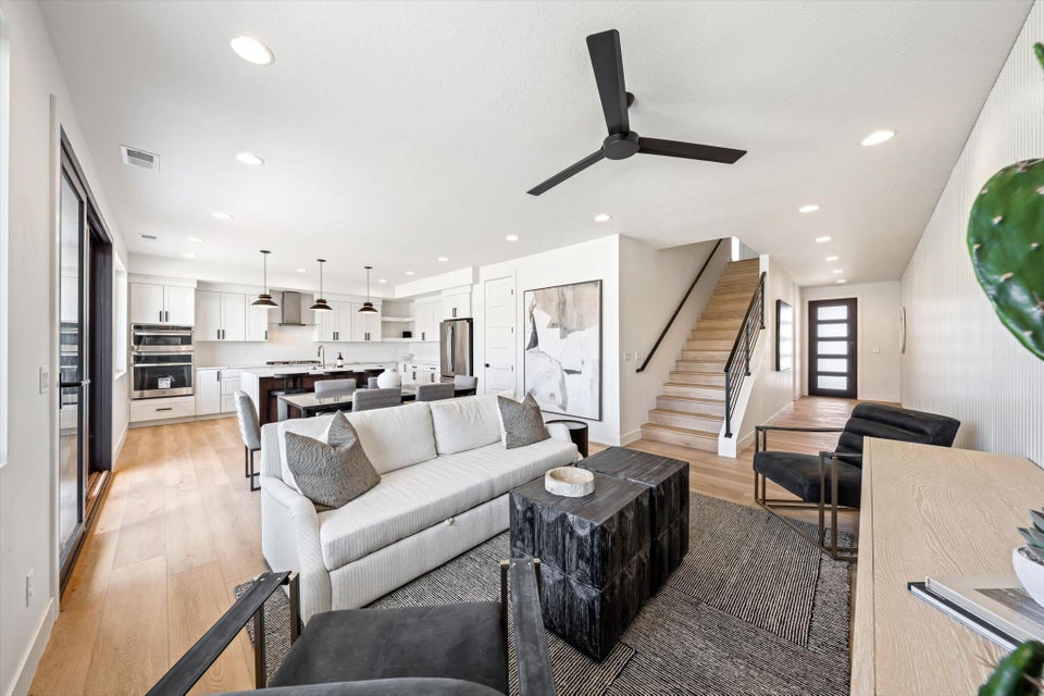 Open-concept living area featuring light wood-finish flooring, recessed lighting, and a modern ceiling fan