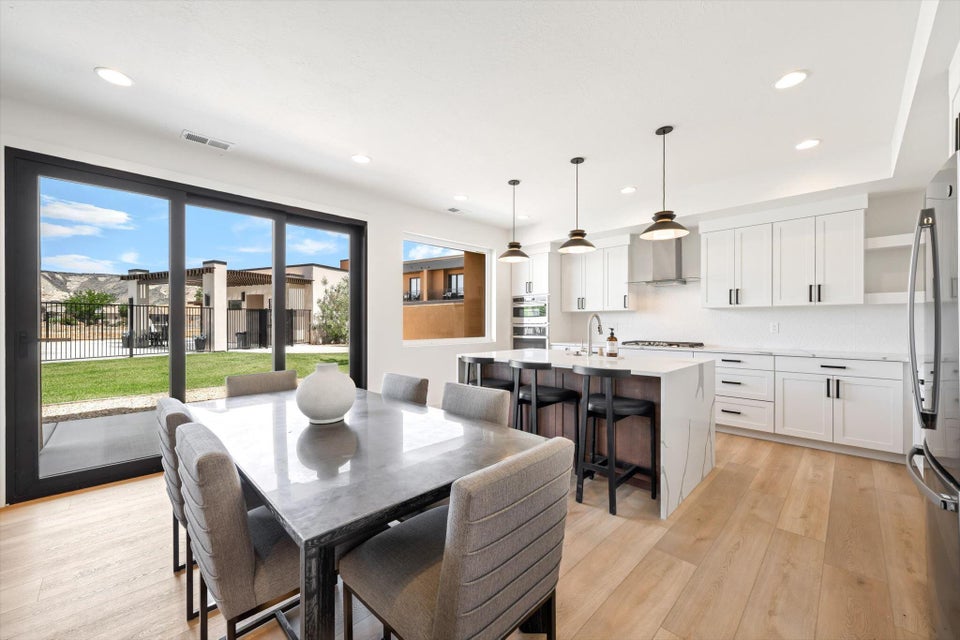 Open-concept living space featuring light wood-finish flooring, white cabinetry with dark hardware, a center island with bar seating, and a stainless steel appliance suite