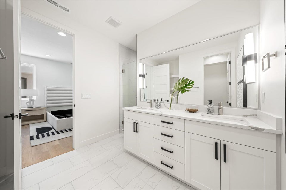 Contemporary bathroom featuring a double vanity with white cabinetry and black hardware