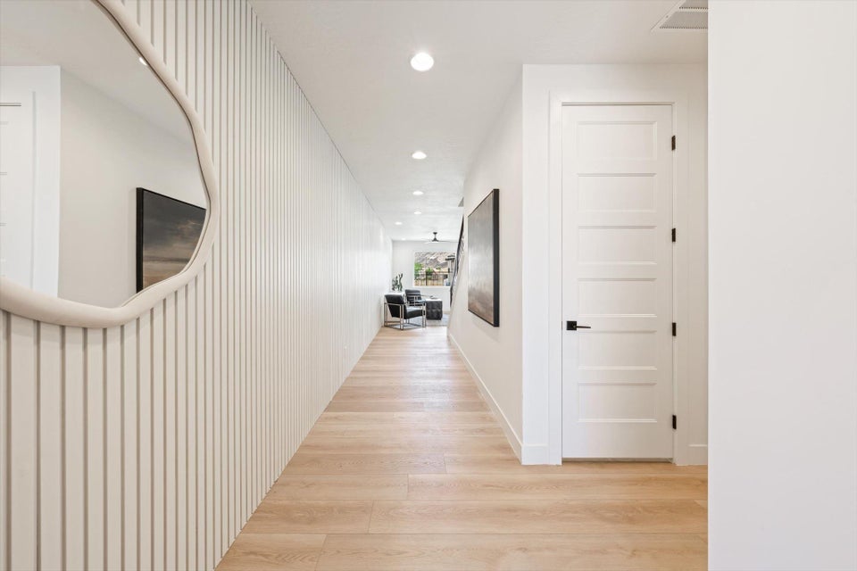 Hallway with light wood-finish flooring, recessed lighting, and a textured accent wall