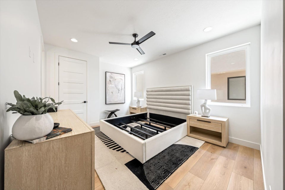 Bright interior space featuring light wood-finish flooring, white walls, and a contemporary ceiling fan with integrated lighting
