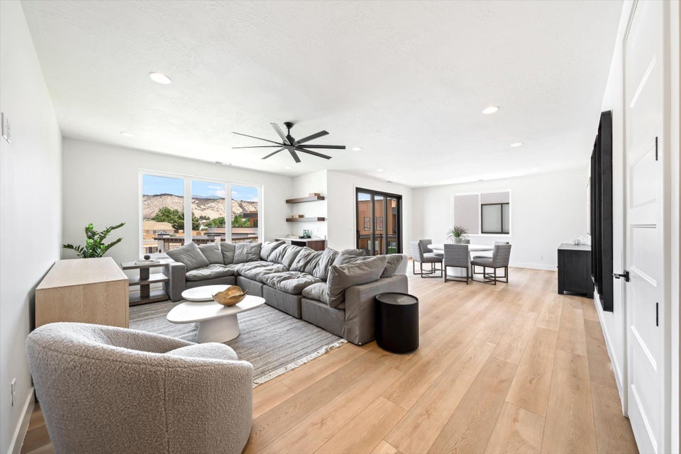 Open-concept living space featuring wood-finish flooring, recessed lighting, and large windows showcasing a mountain backdrop