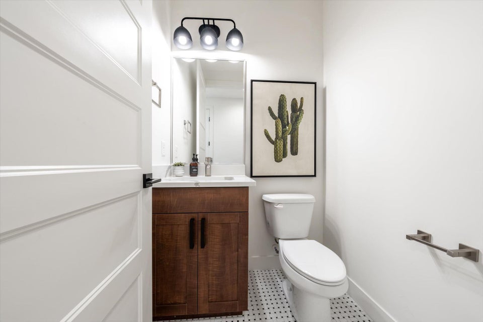 White paneled door opening to a compact bathroom featuring a dark wood-finish vanity with a white countertop and rectangular sink