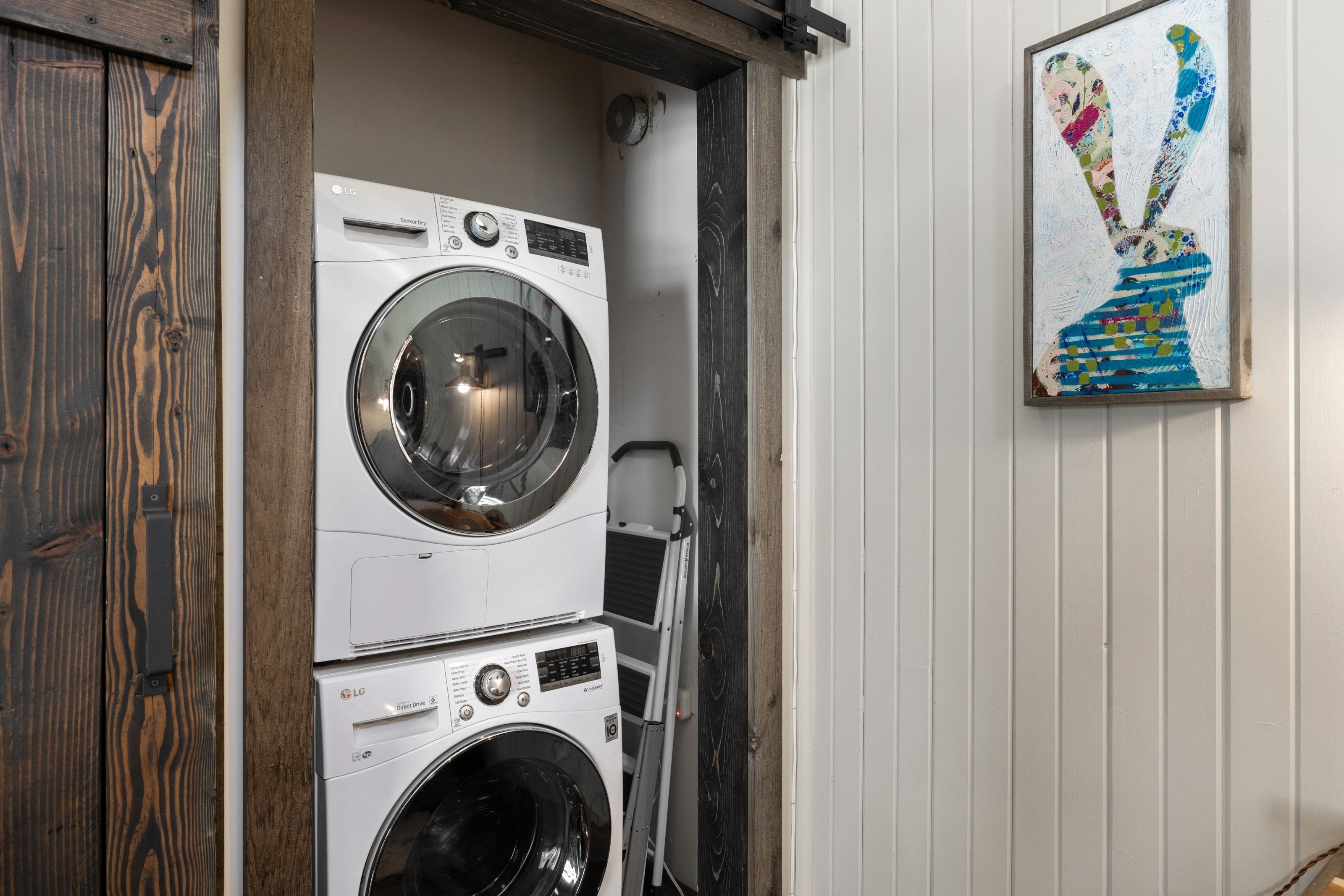 Laundry area featuring a barn door, stacked washer and dryer, and wooden walls