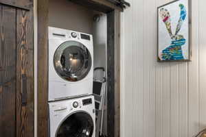 Laundry area featuring a barn door, stacked washer and dryer, and wooden walls