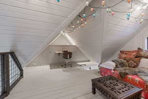 Additional living space featuring hardwood / wood-style flooring, vaulted ceiling, and wood walls