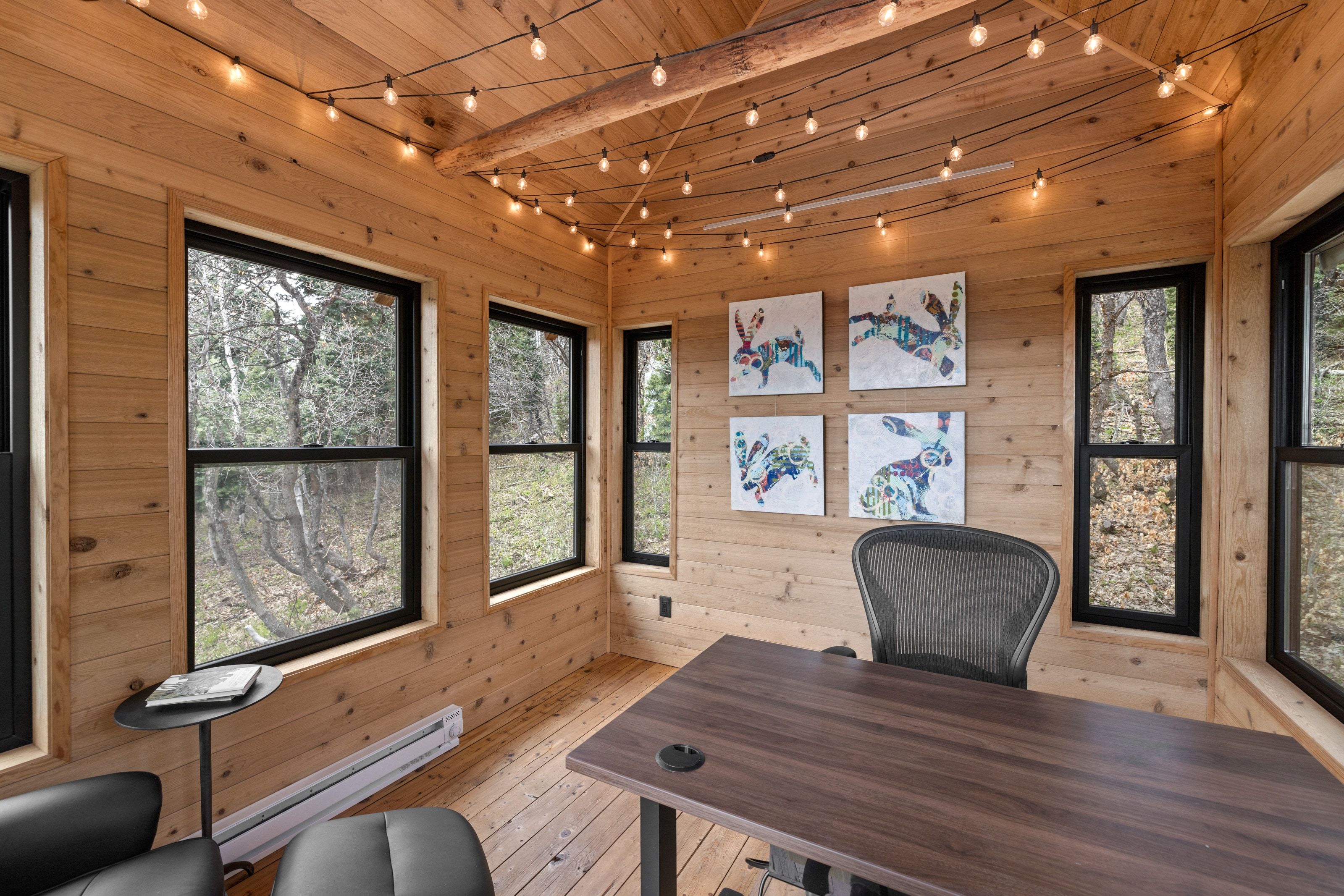 Office space with a baseboard radiator, track lighting, wood walls, light wood finished floors, and wood ceiling