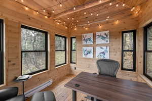 Office space with a baseboard radiator, track lighting, wood walls, light wood finished floors, and wood ceiling