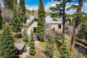 Rear view of house with a standing seam roof, view of scattered trees, and a balcony