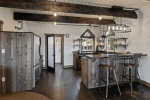 Kitchen featuring open shelves, a peninsula, a wooden ceiling with exposed beams, freestanding refrigerator, and pendant lighting
